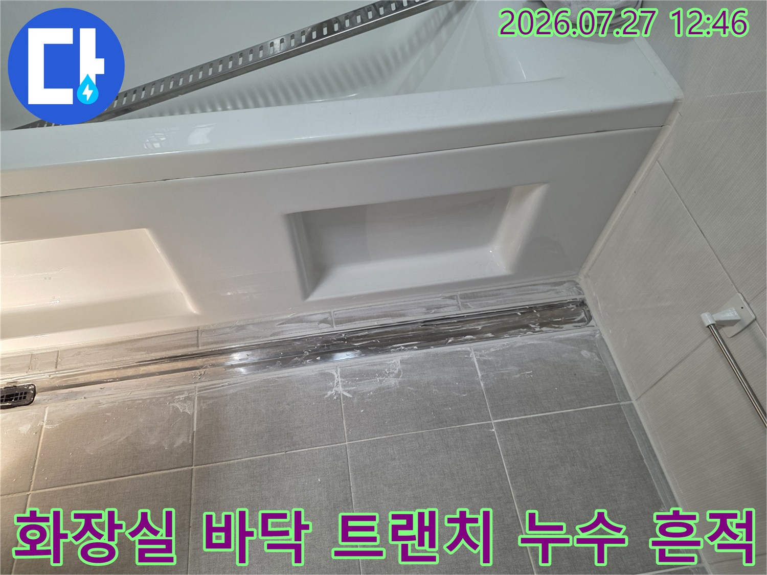 흰색 타일 바닥에 설치된 금속제-트랜치 배수구 주변의 오염과 누수 징후