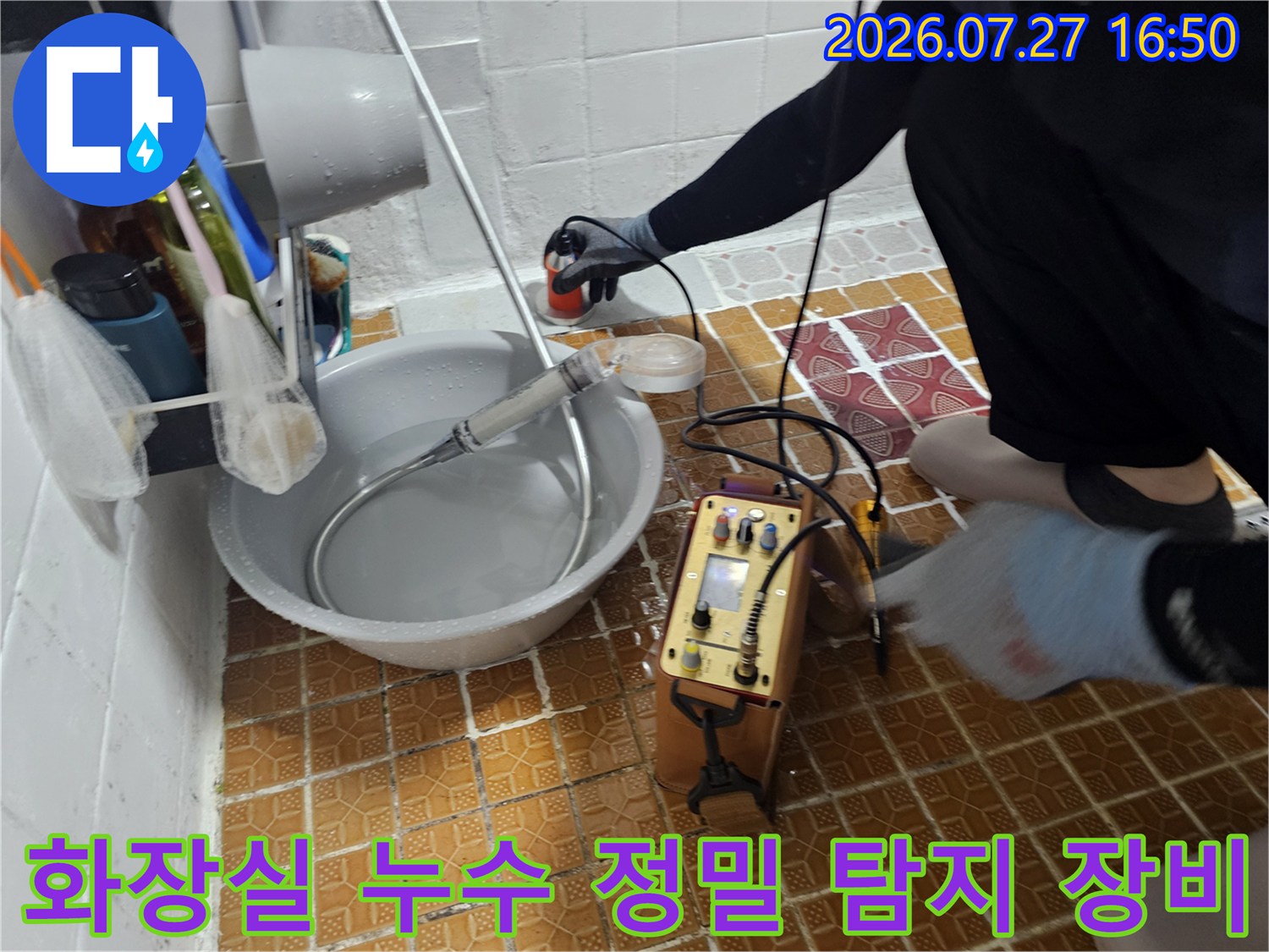 화장실 바닥에 놓인 공압 테스트 장비와 배관 연결 호스-누수 지점을 찾기 위한 과정