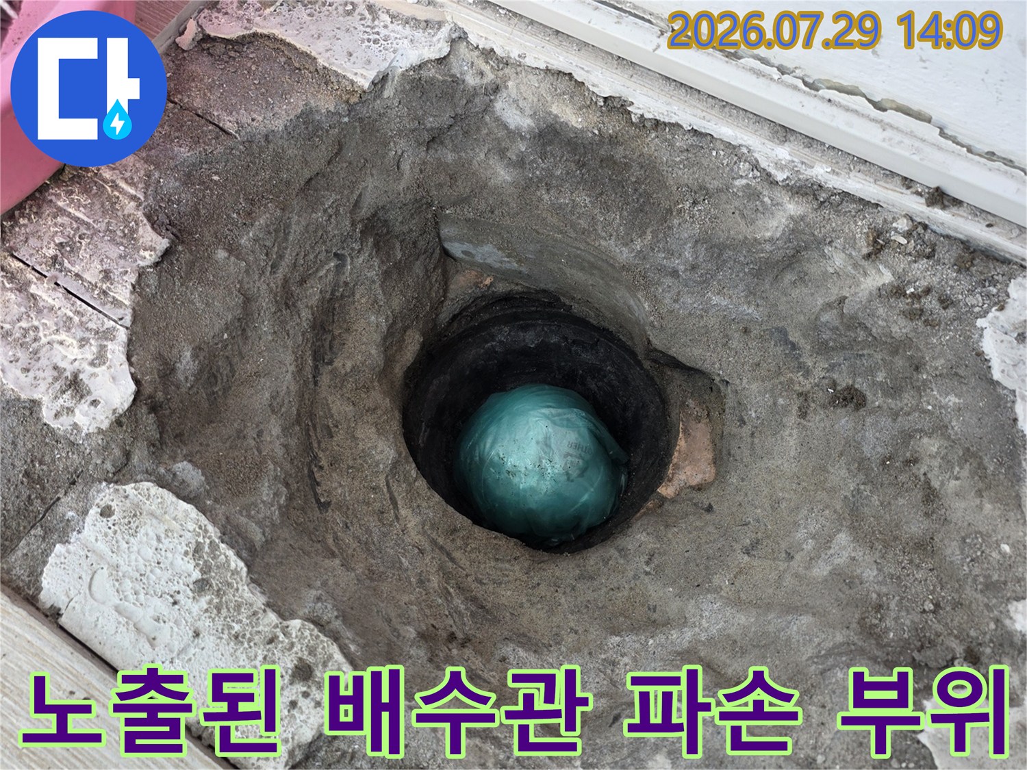 노출된 검은색 배수관과 주변 시멘트 파쇄면