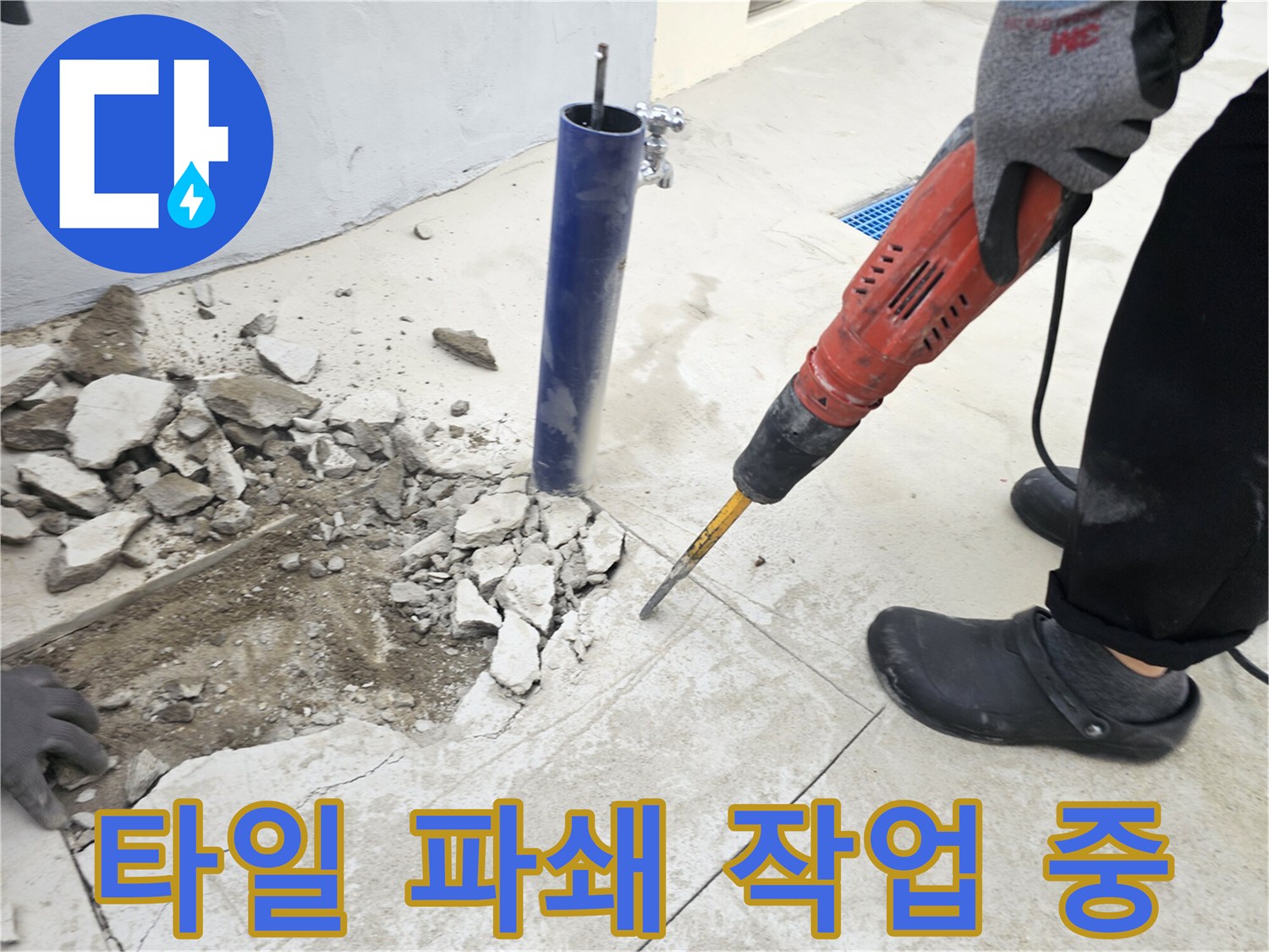 전동 공구를 사용하여 화장실 타일을 깎아내어 배관을 노출시키는 장면