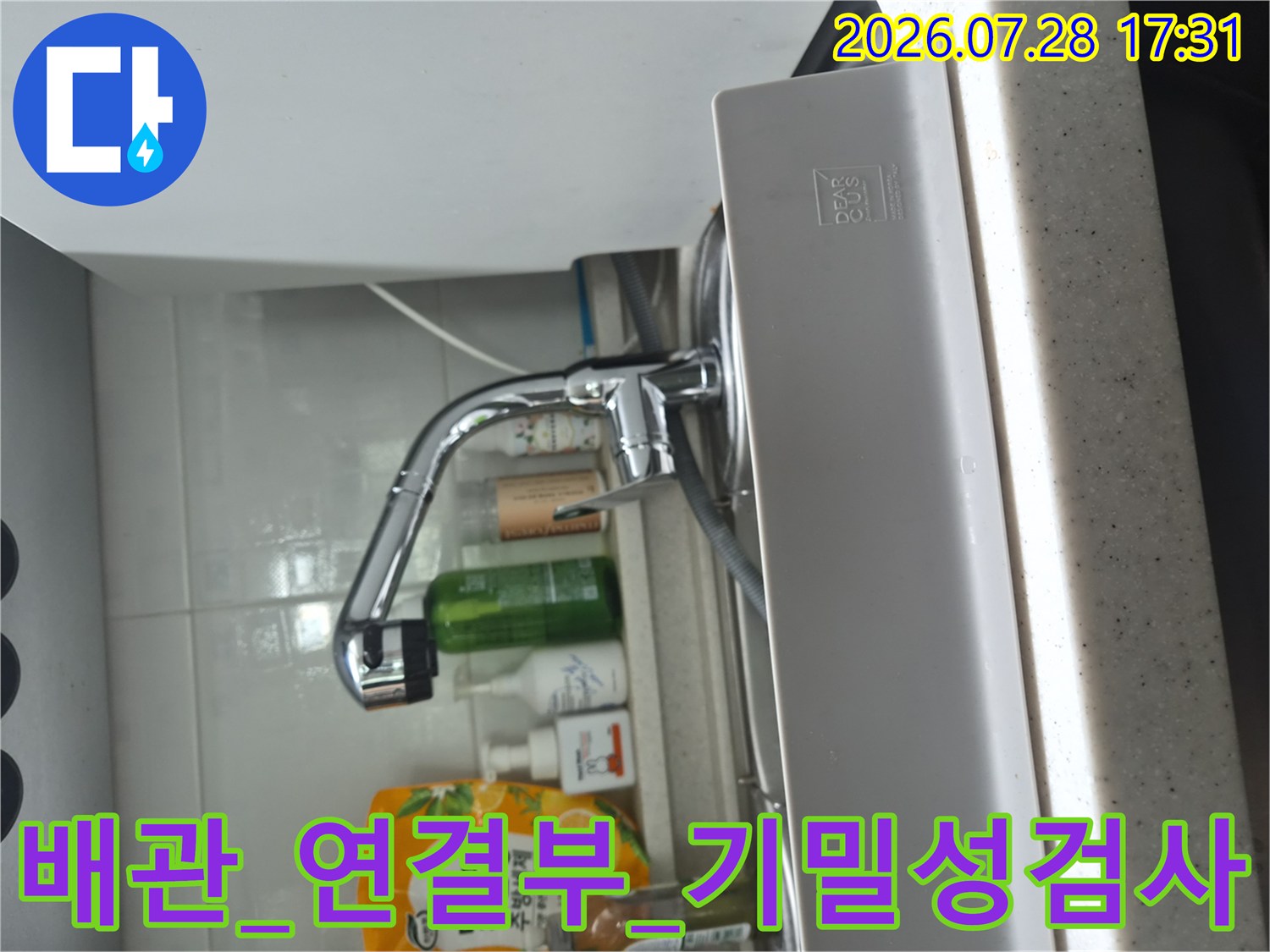 싱크대 하부에서 식기세척기용 수전과 배관이 만나는 지점의 누수를 점검하는 모습입니다.