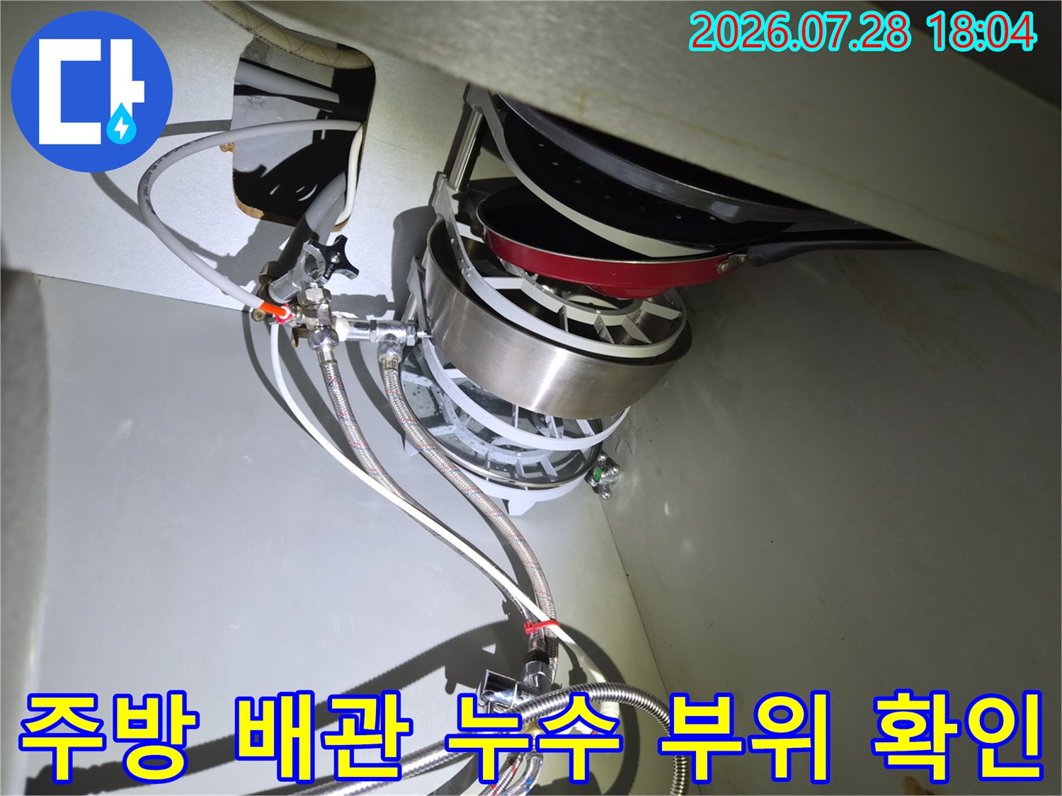 싱크대 하부의 복잡한 급수 라인과 식기세척기 연결부를 정밀 점검하는 모습입니다.