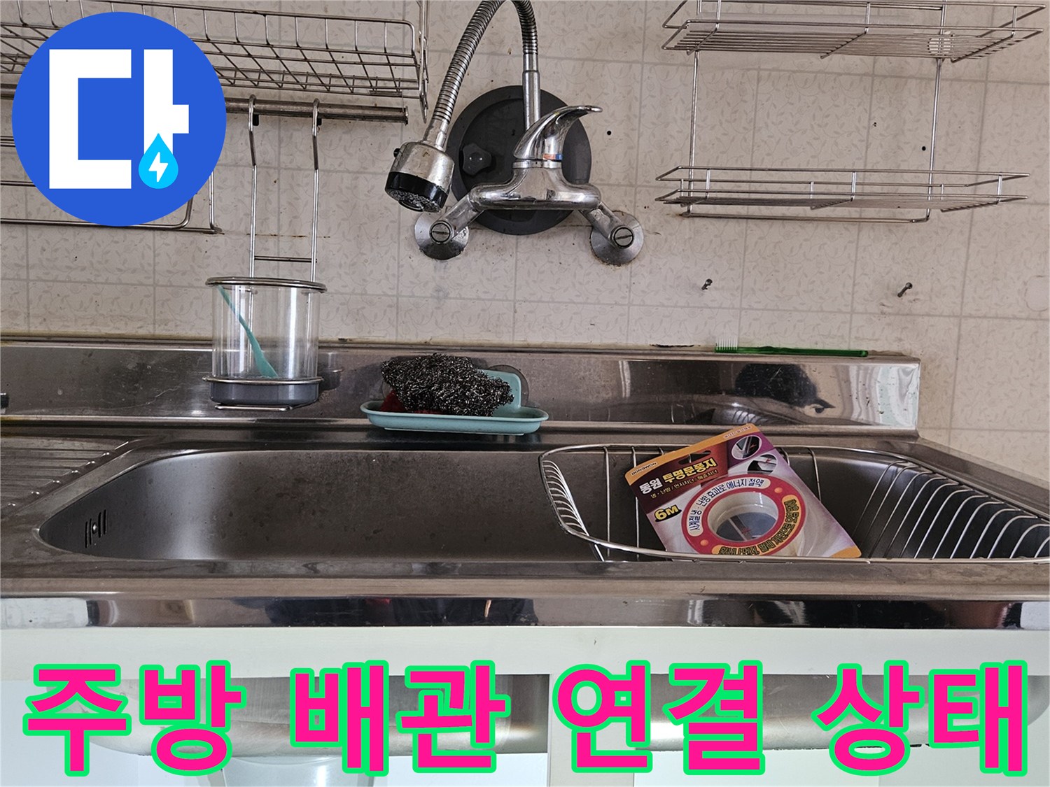 싱크대 하부장 내부에 노출된 수전 호스와 배수 관로의 모습입니다.