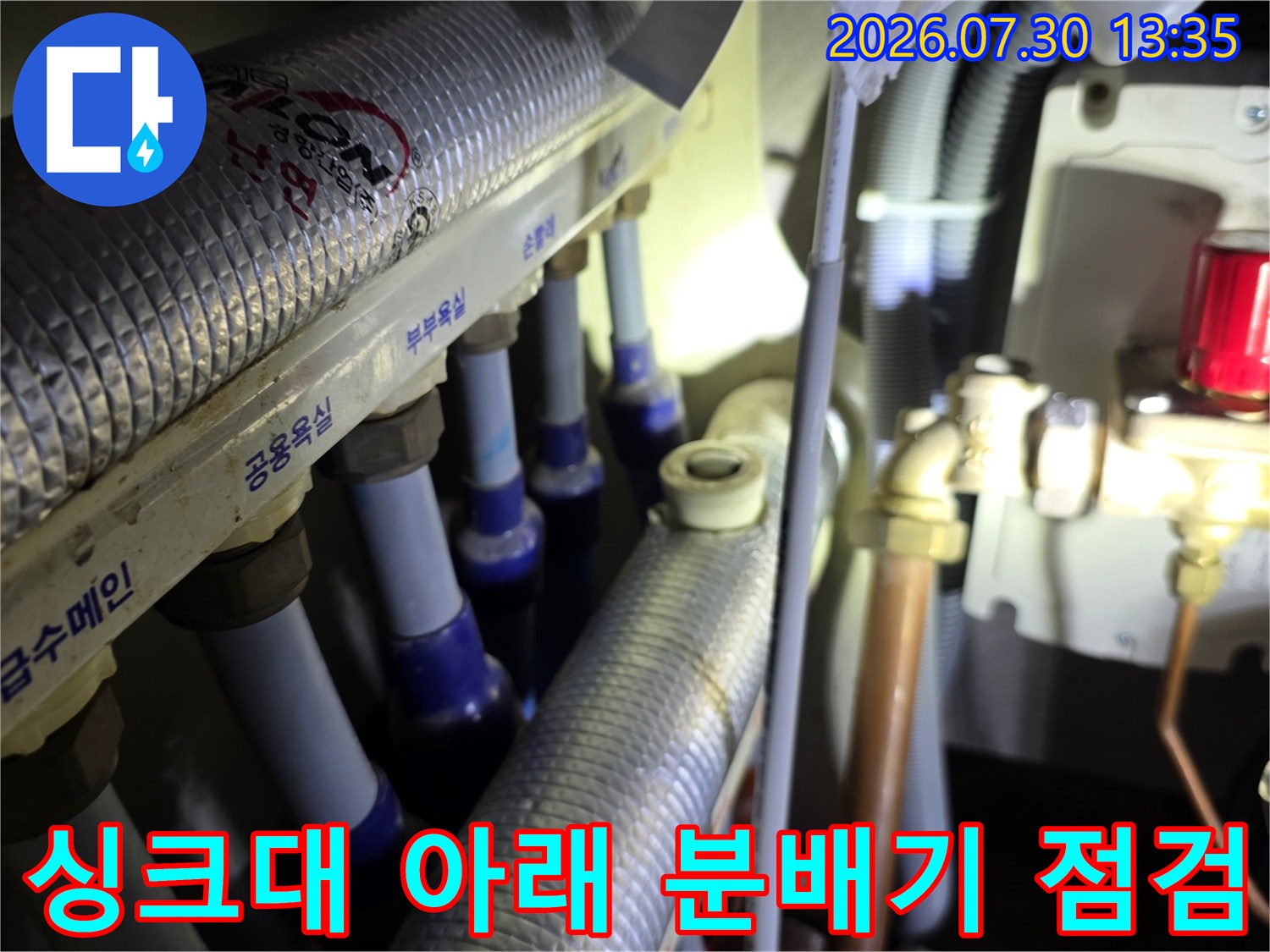 싱크대 하단 공간에서 온수 밸브 및 배관 연결 부위 수리 현장