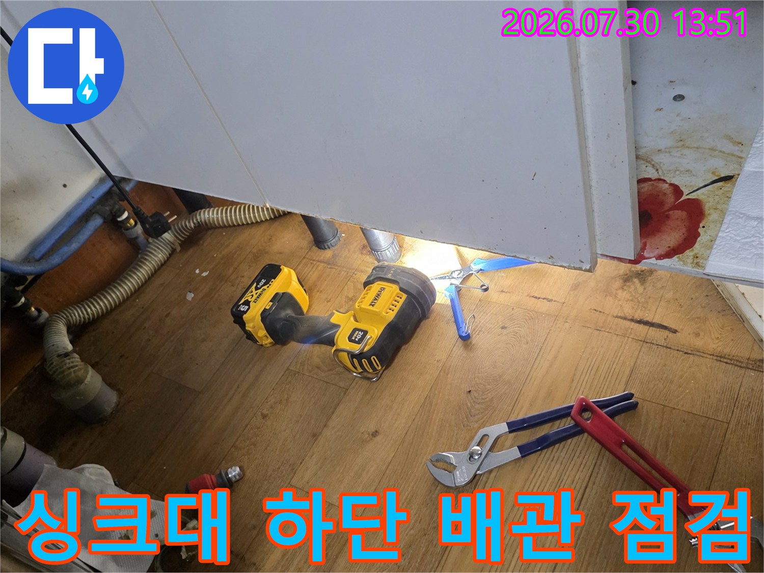 싱크대 하부장에서 작업 중인 급수 배관과 공구들