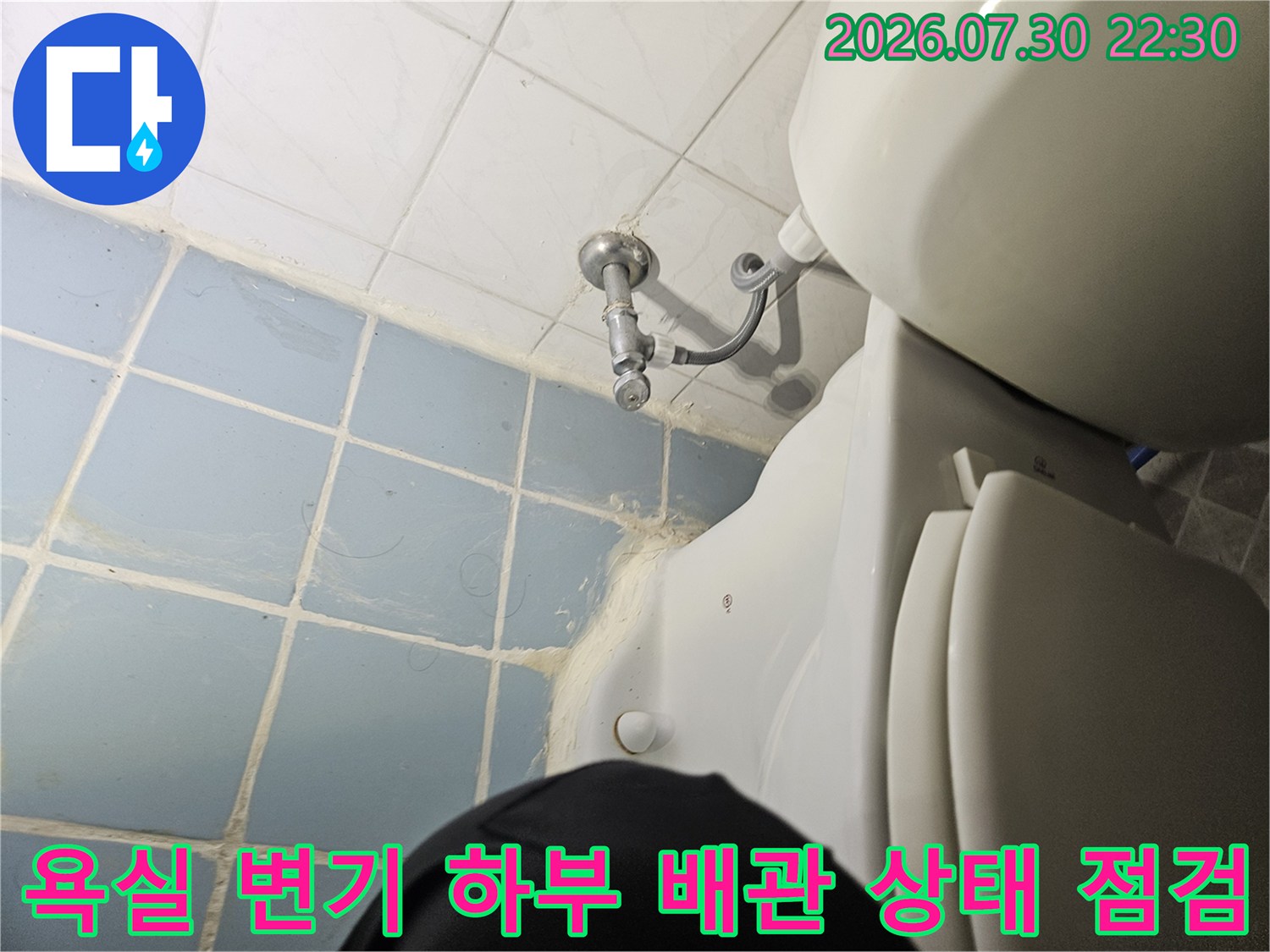 변기 아래로 노출된 배수 시스템의 연결 부위와 주변 오염도를 체크하는 모습