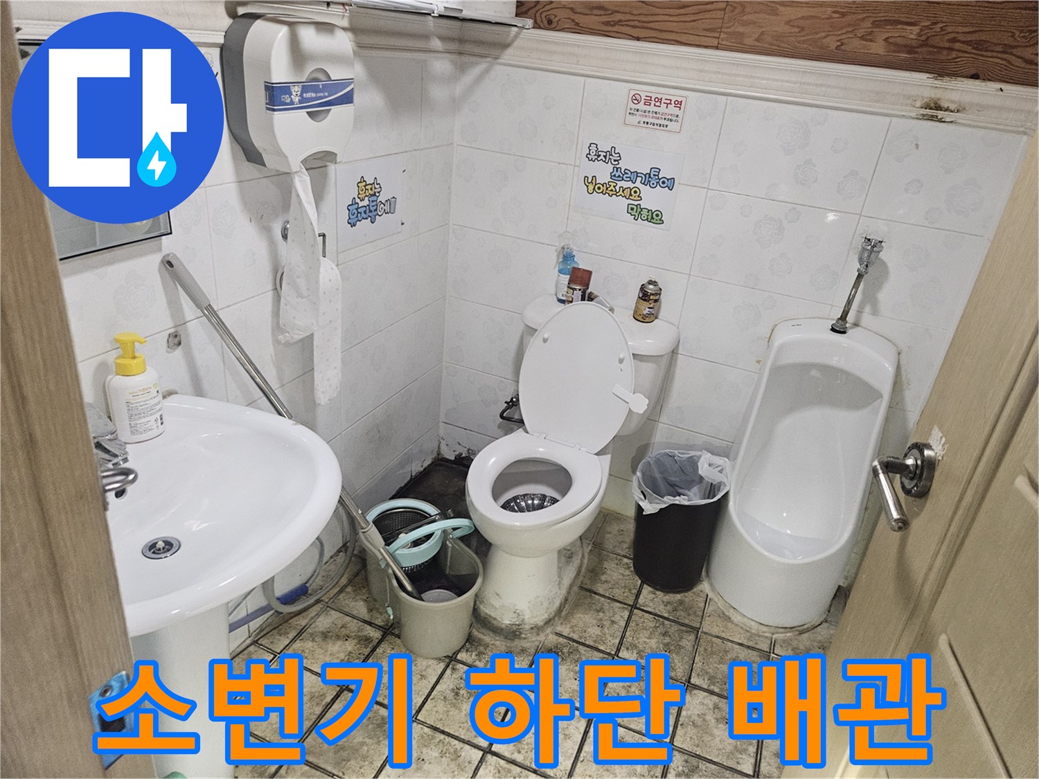 부식된 소변기 연결 배관과 주변의 오염된 타일 상태를 촬영한 사진입니다.