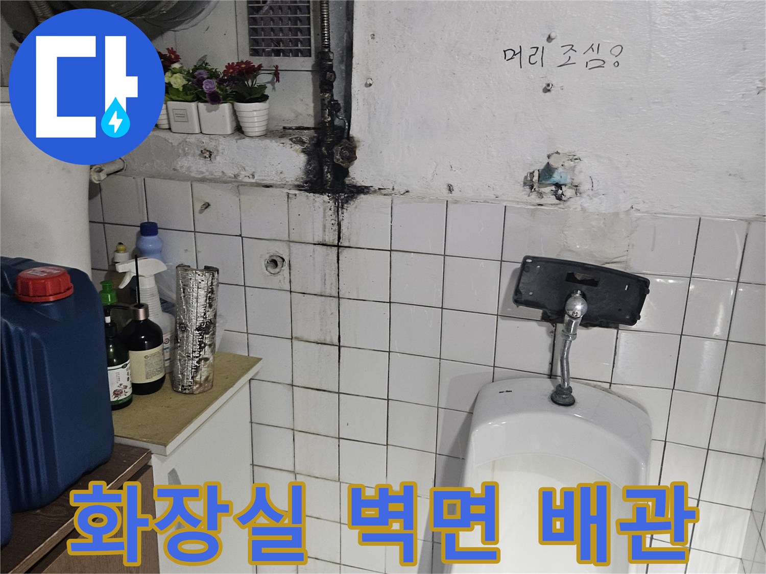 소변기 뒤쪽 벽면에 설치된 노후된 급수 배관 및 연결부