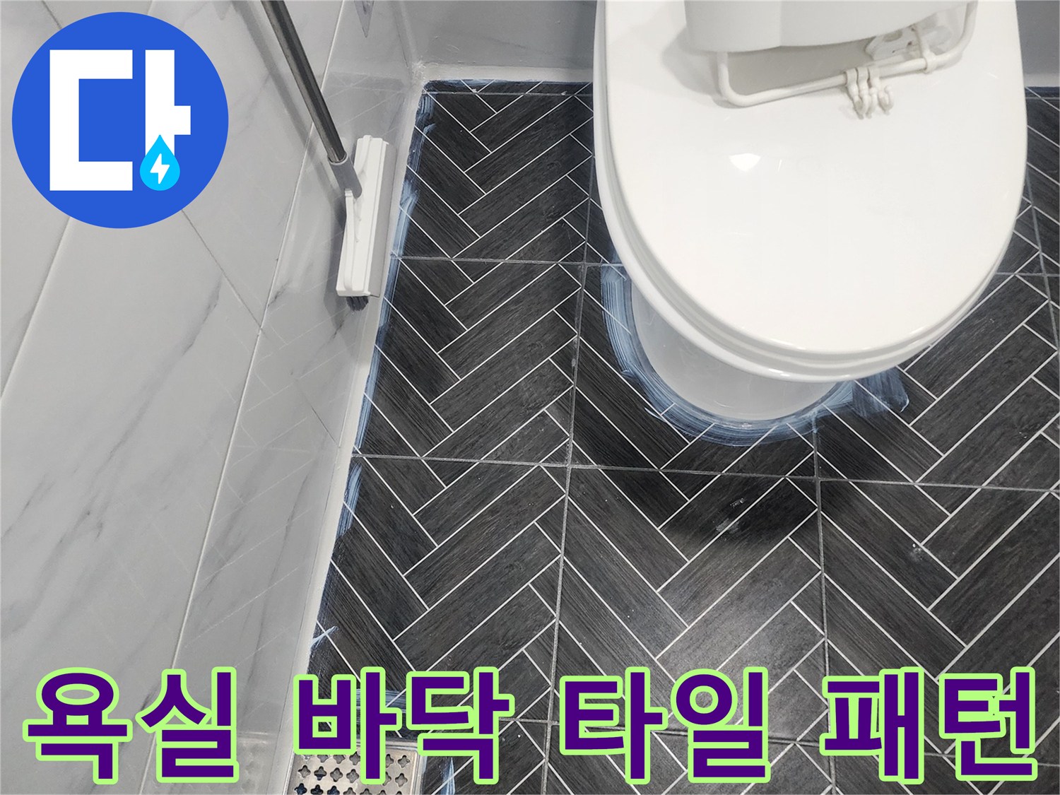 어두운 톤의 헤링본 욕실 타일과 배수구 모습