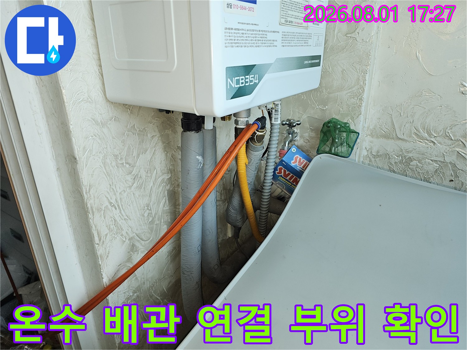 싱크대 아래쪽 온수 배관과 계량기 주변의 복잡한 배관 구조를 점검하는 모습