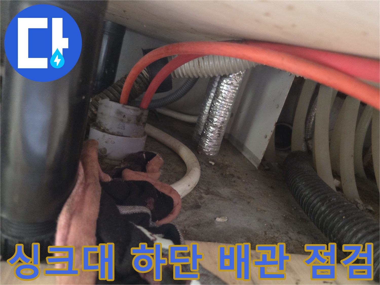 복잡하게 연결된 싱크대 하단 배관과 호스들
