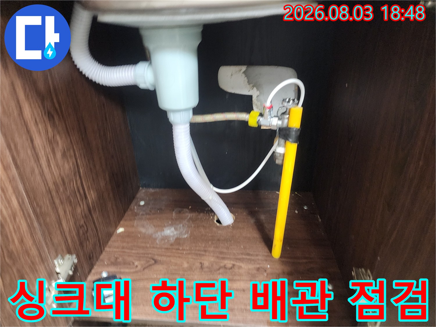 싱크대 아래쪽 노란색 배관과 흰색 호스가 연결된 모습