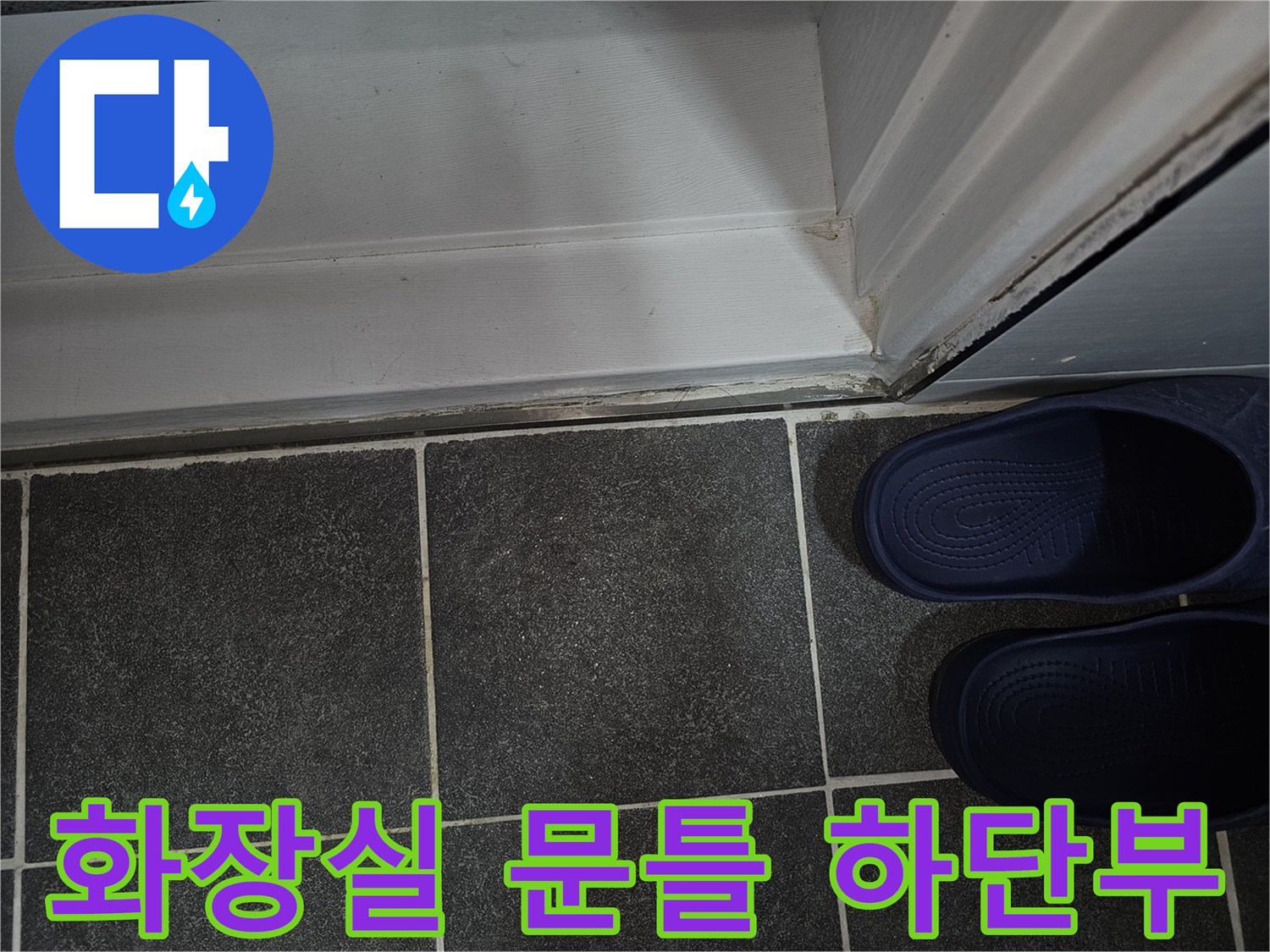 어두운 색상의 욕실 타일과 흰색 도어 프레임의 경계 지점