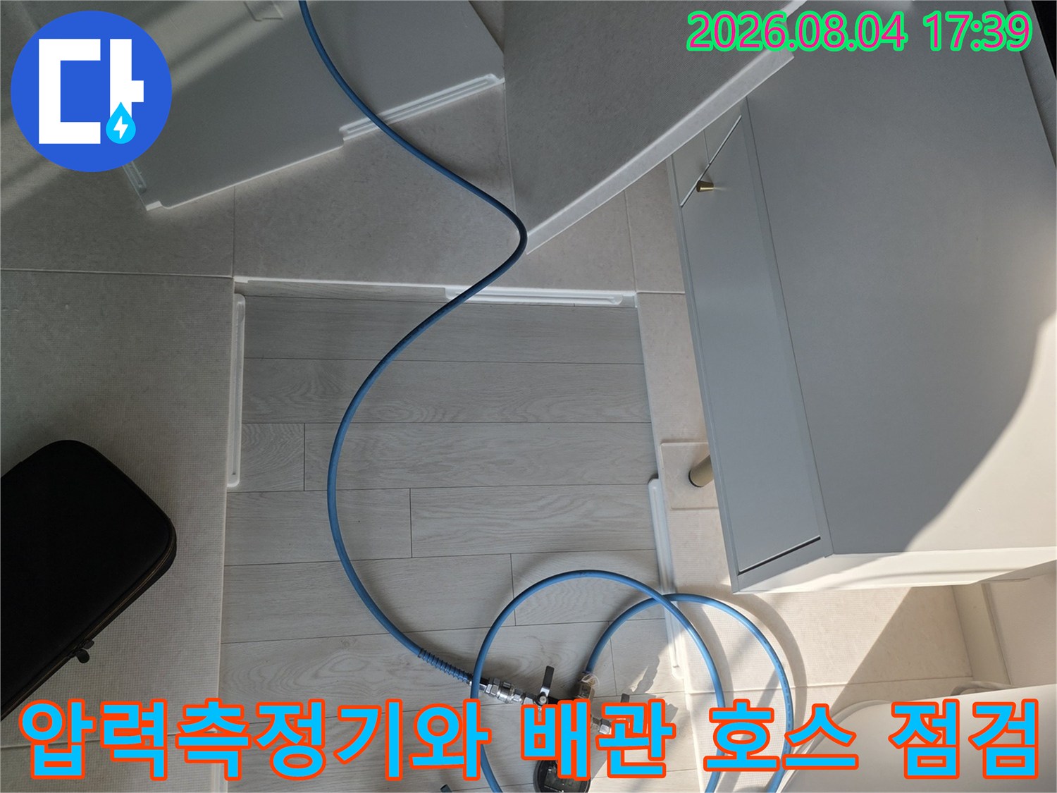 압력 게이지가 연결된 파란색 호스와 장비로 배관 상태를 점검하는 모습