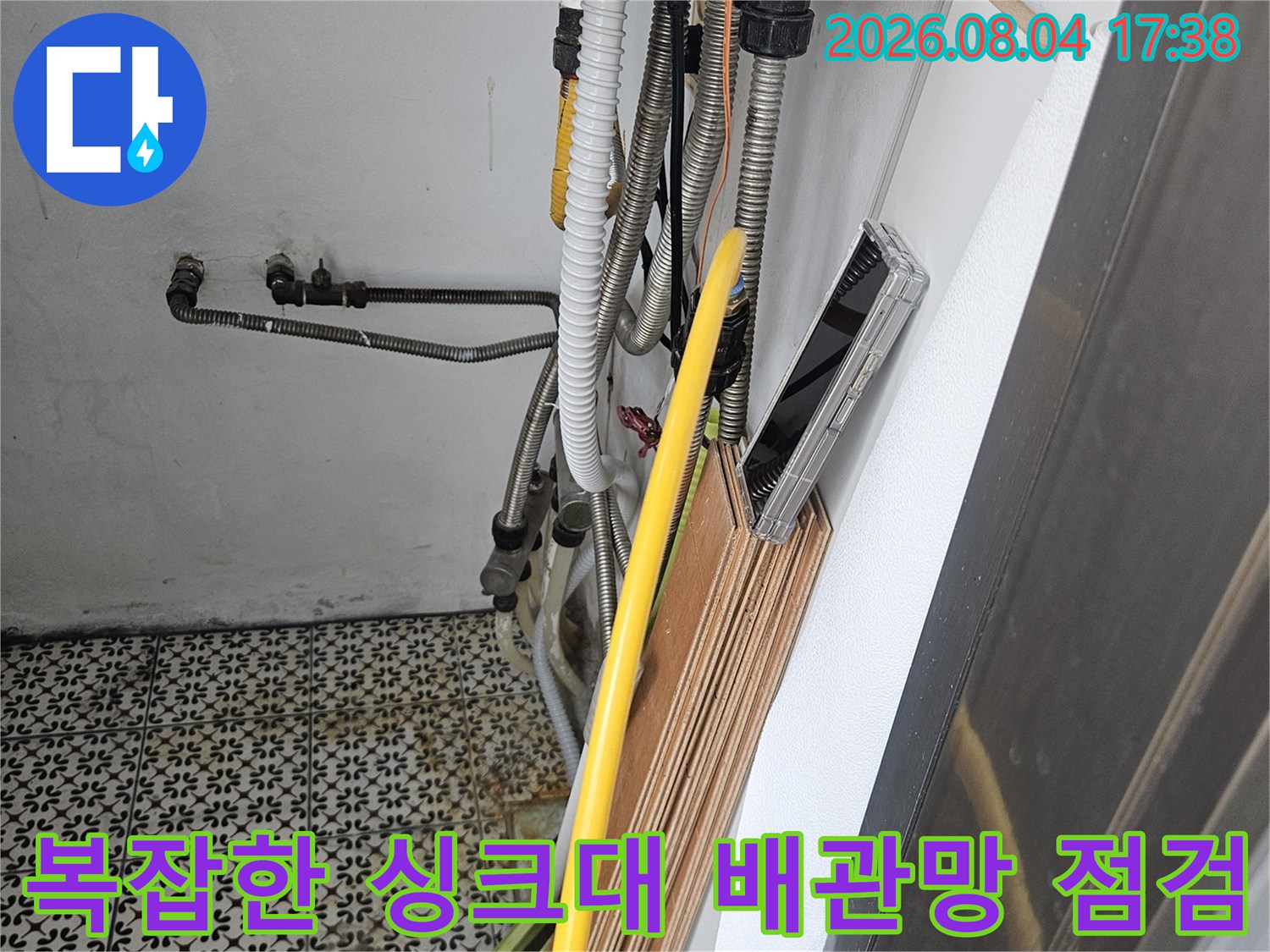주방 하단에 노란색 보온재를 씌운 온수 배관과 여러 가닥의 선들이 섞인 모습