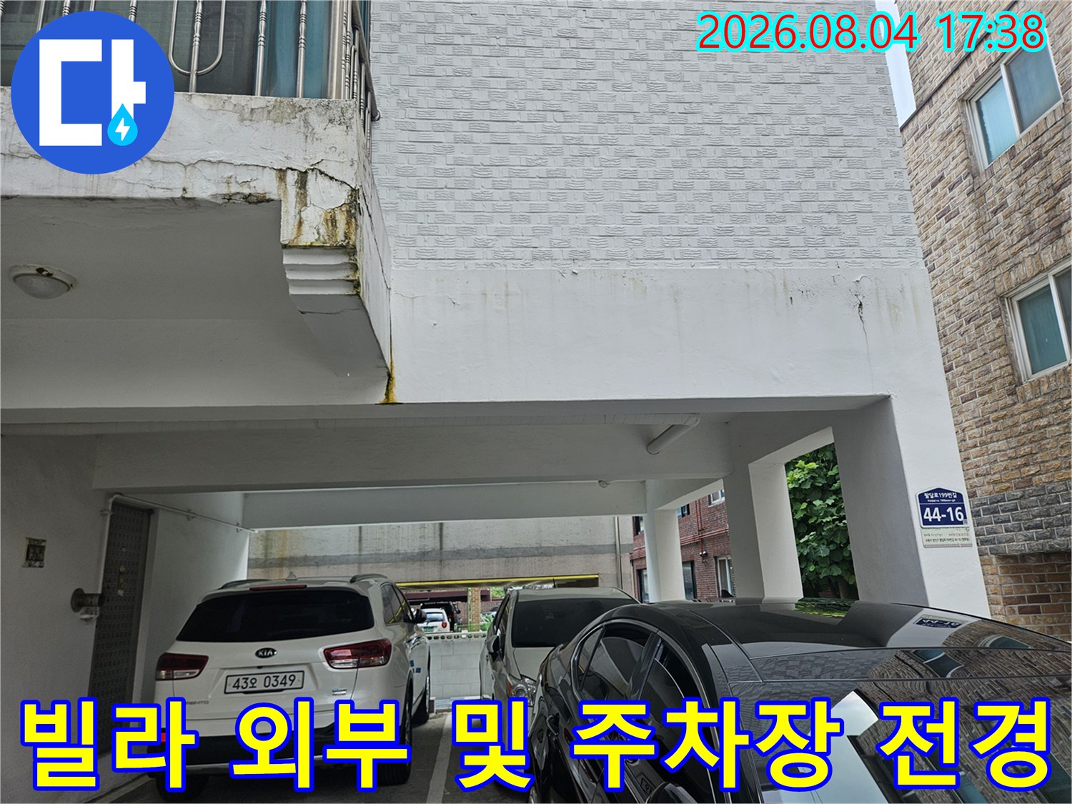필로티 구조 건물의 입구와 차량이 주차된 외부 전경