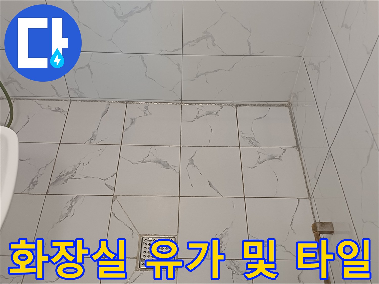 흰색 대리석 무늬 타일과 금속 배수구 덮개가 있는 욕실 바닥입니다.
