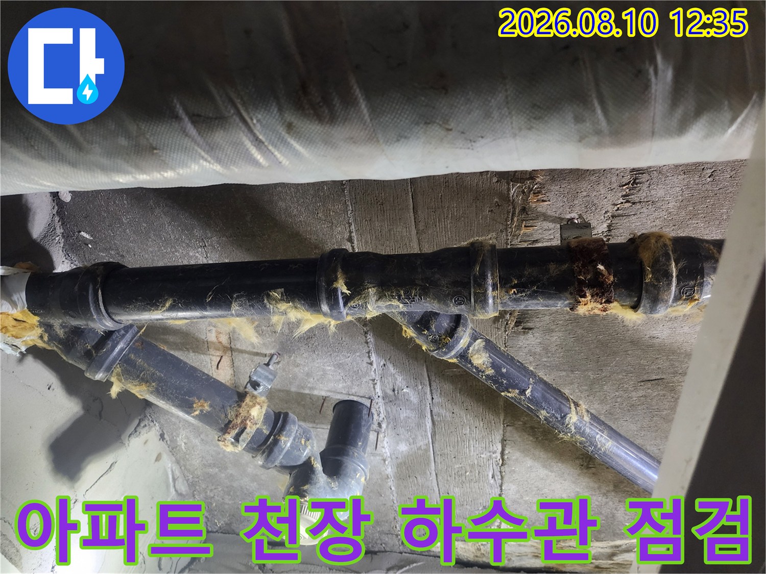 어두운 천장 내부 공간에 설치된 검은색 배관과 낡은 마감재 상태