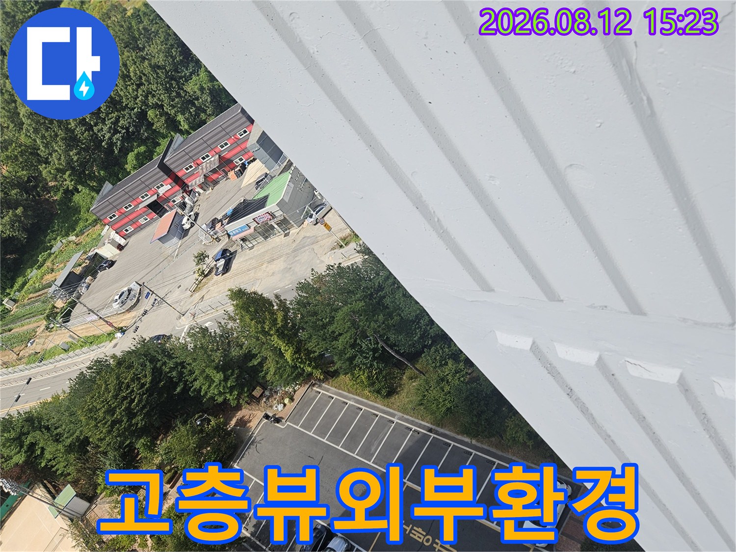 건물 옥상 근처 난간에서 내려다본 주차 구역과 주변 건물들-광각 사진