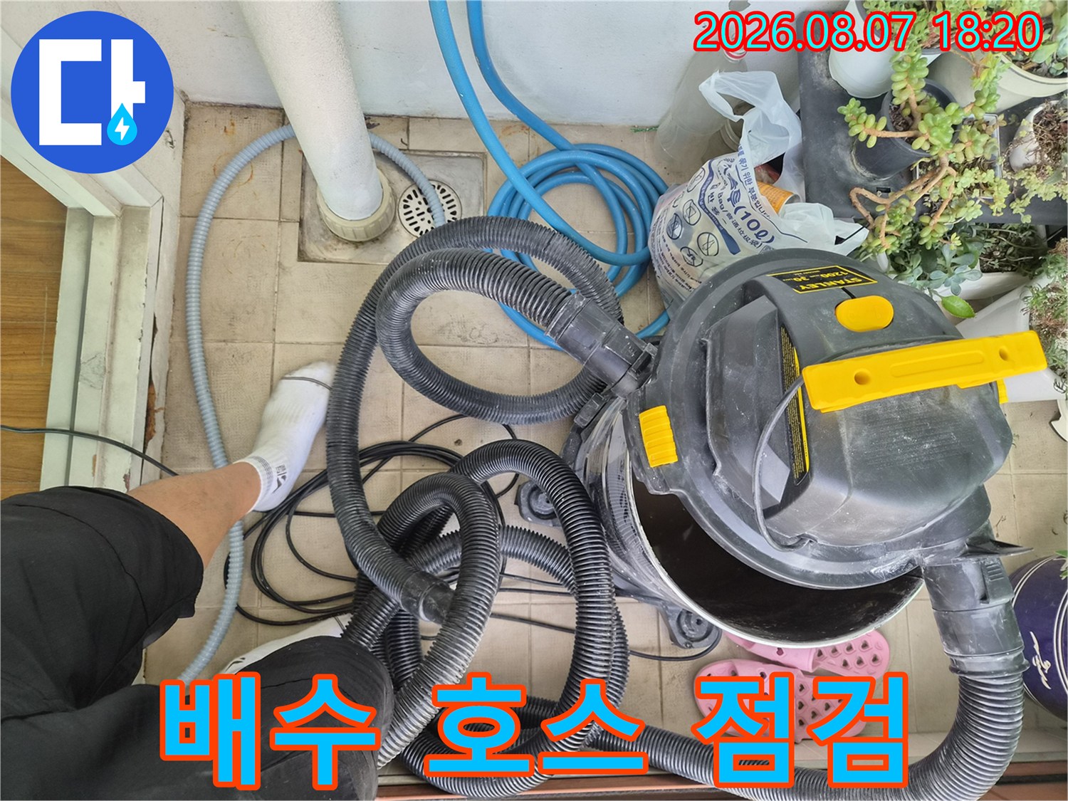 파란색 배수 호스와 검은색 흡입 장비가 놓여 있는 작업 현장입니다.