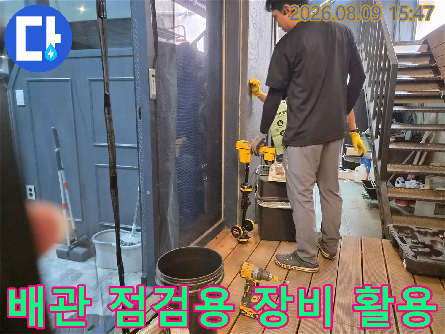 전동 드릴과 수거 통 등 작업 도구를 사용하여 하수관을 점검합니다.