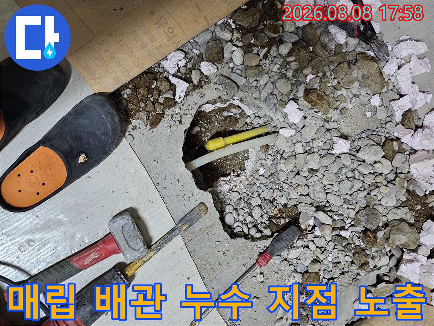 콘크리트 파편 사이로 드러난 손상된 배관과 현장 작업 도구의 모습