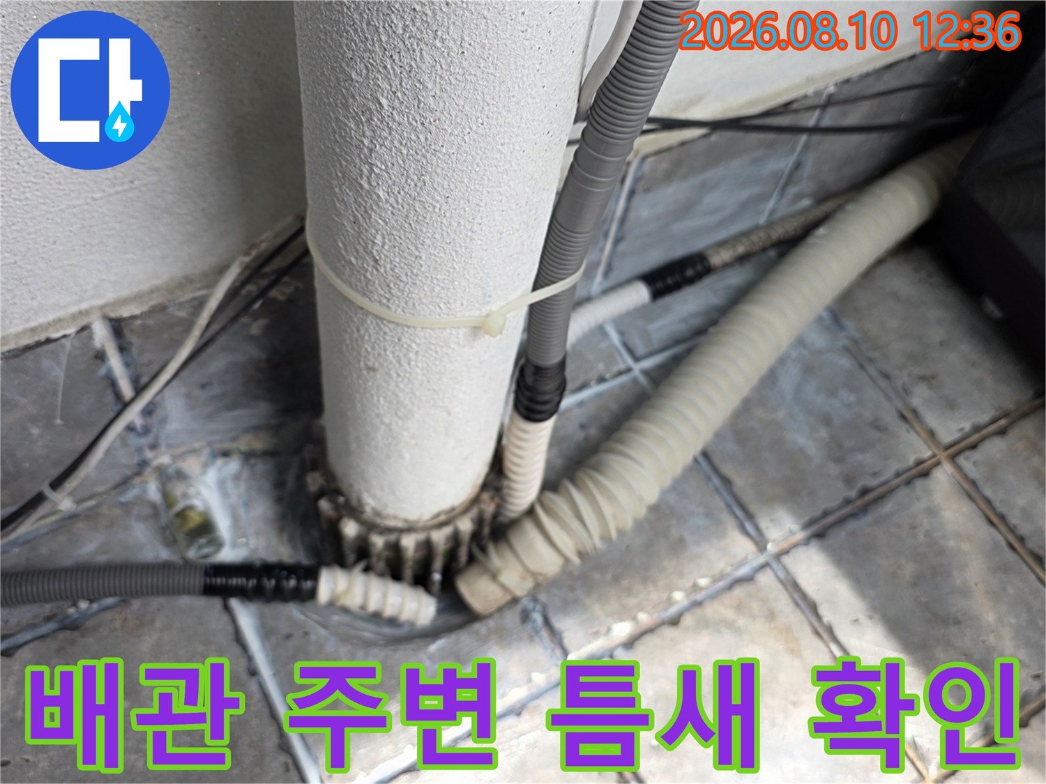 배관 하단부와 타일 사이의 균열과 습기를 촬영한 사진입니다