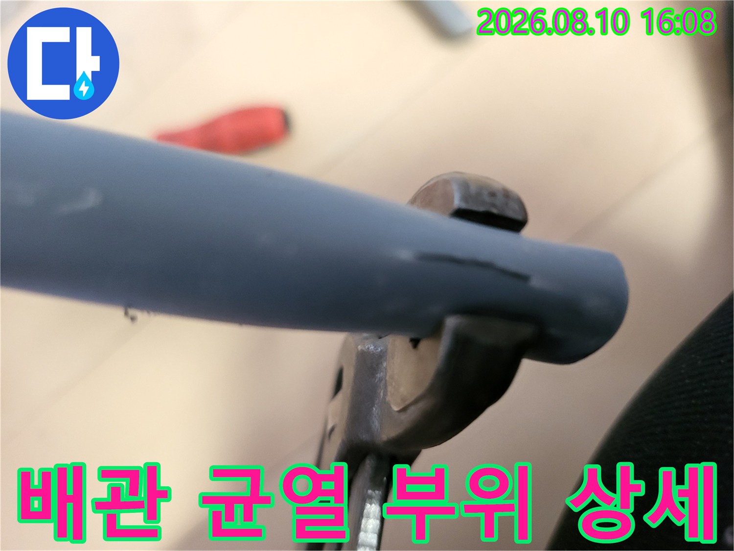 파란색 배관에 발생한 길쭉한 균열을 근접 촬영한 사진입니다.