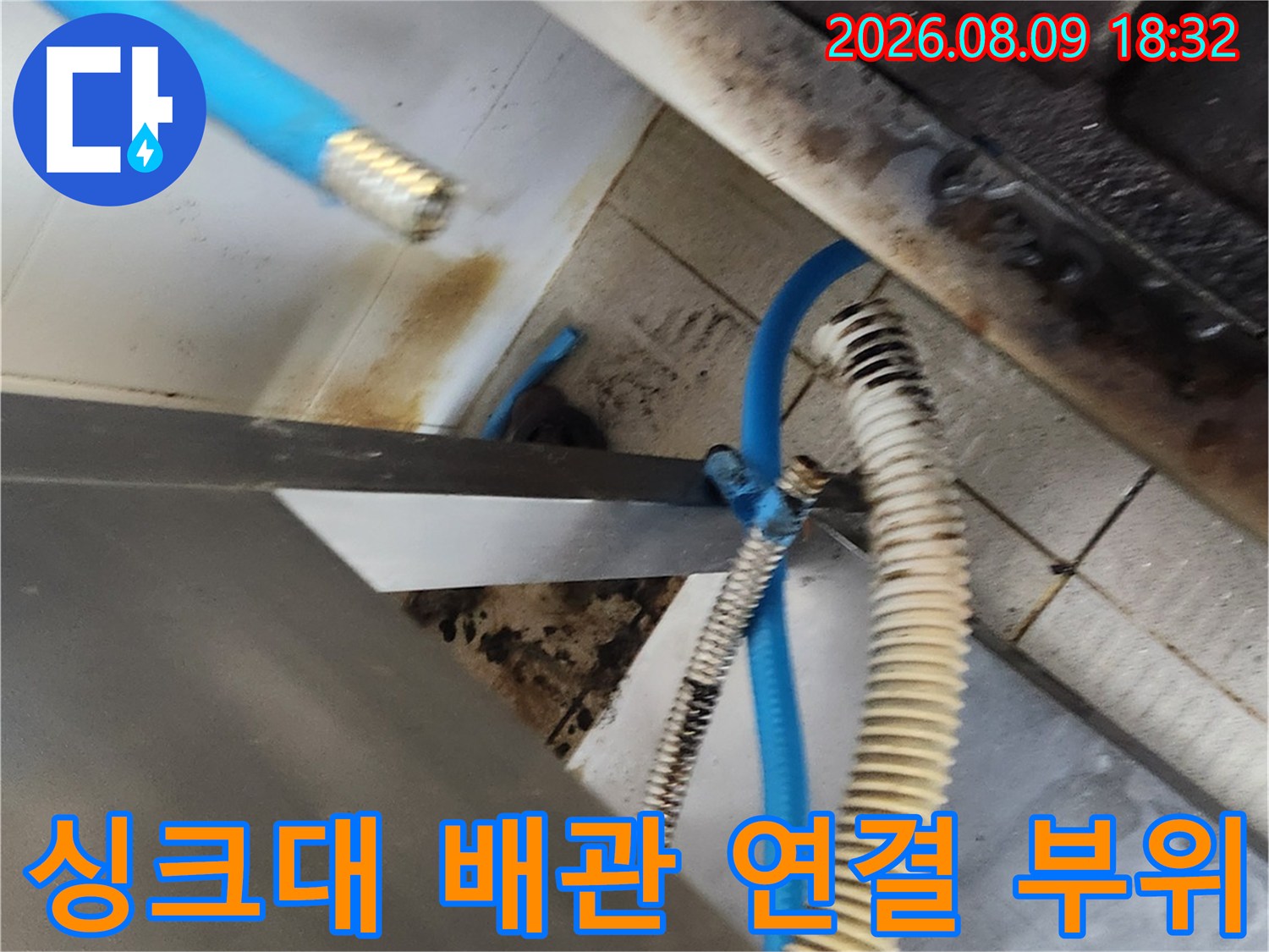 싱크대 하단부의 파란색 호스와 금속 샤워 호스 및 밸브 주변