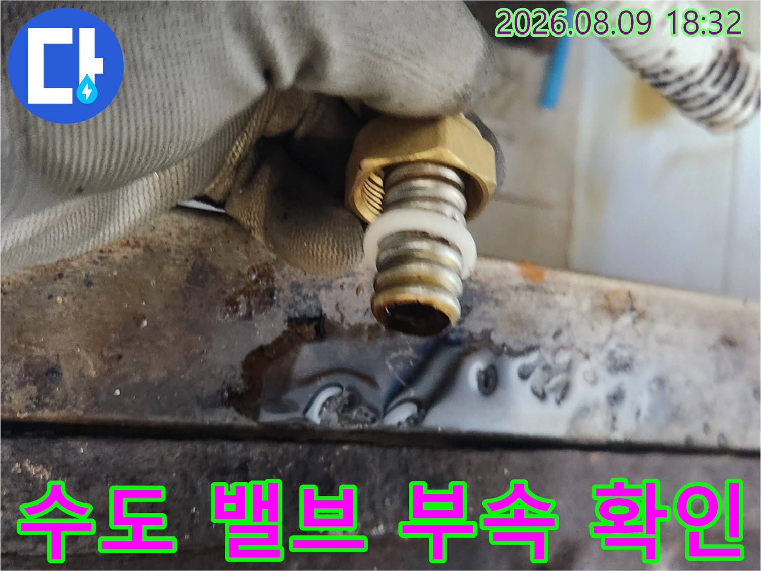 작업자가 탈거된 수도 밸브와 호스를 손으로 잡고 있는 근접 사진