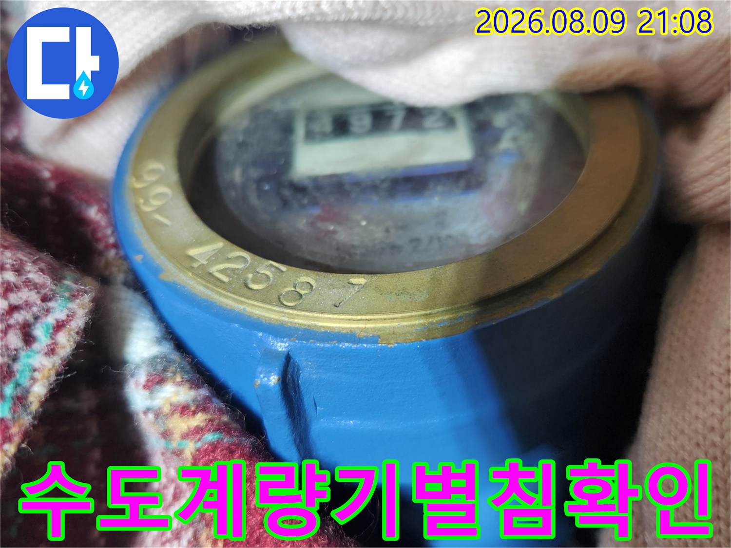 파란색 수도 계량기의 숫자판과 회전하는 별침 부분을 근접 촬영한 사진