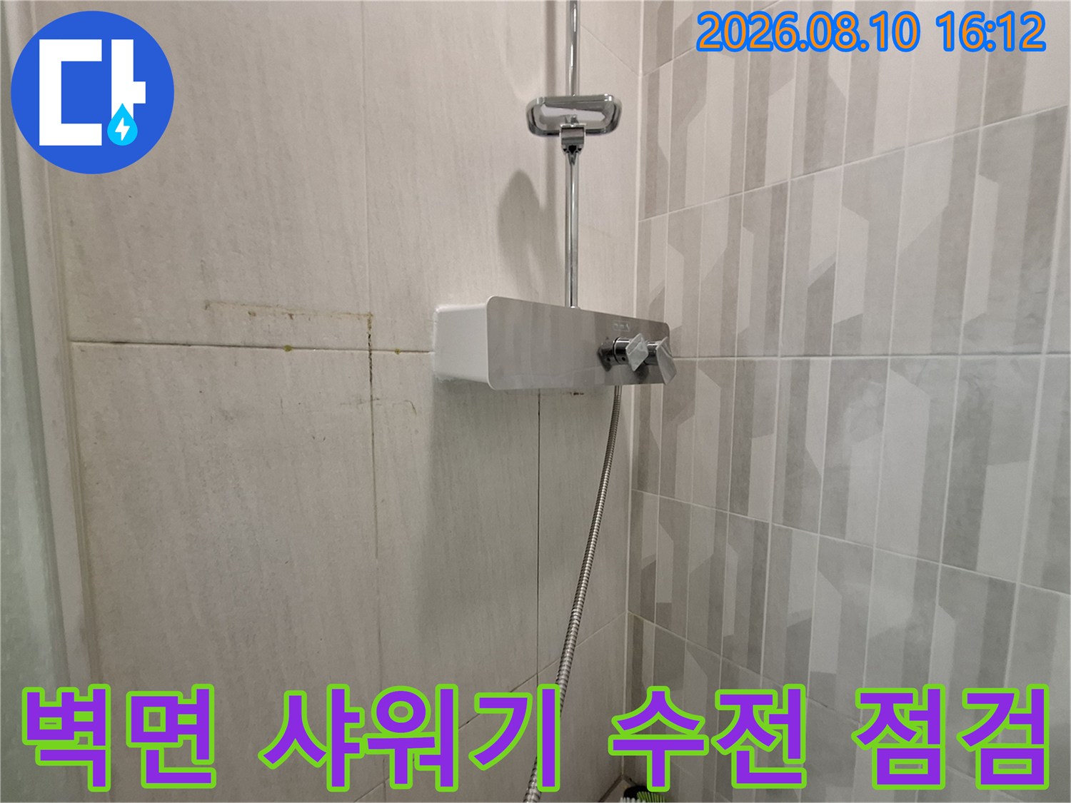 화장실 벽면에 설치된 은색 수전과 샤워기 호스 연결 부위