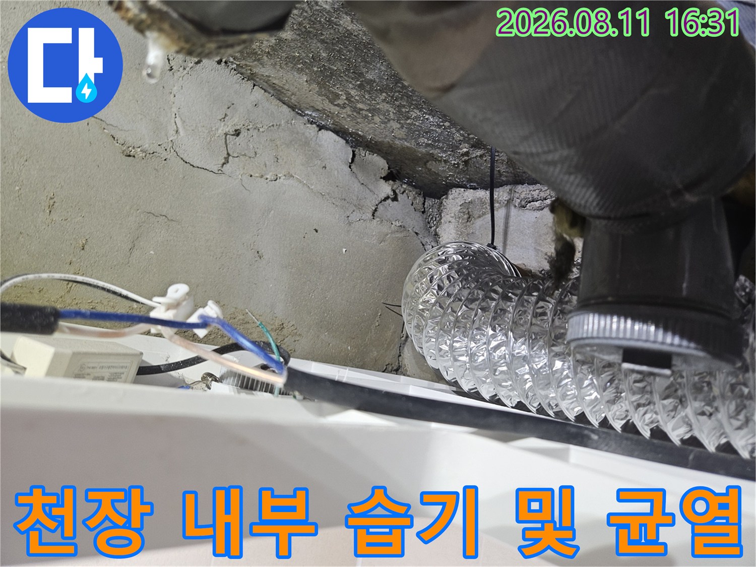 은색 주름관 배관 주변의 젖어 있는 콘크리트 벽면과 갈라진 틈새