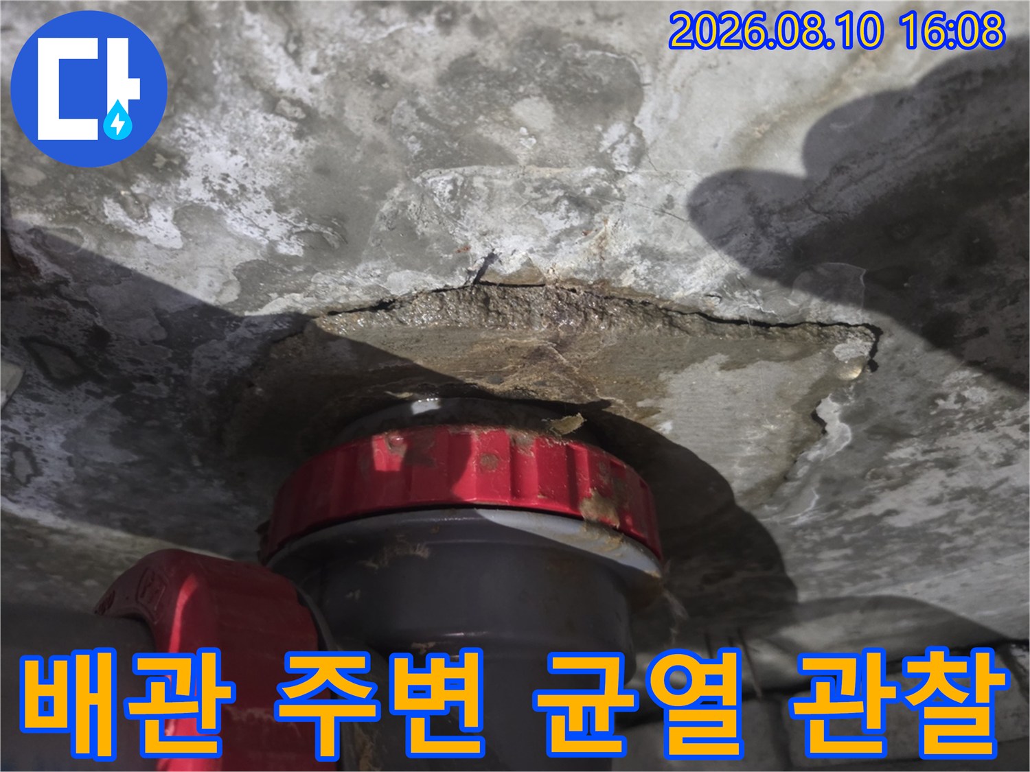 배관 주위의 젖은 얼룩과 미세한 콘크리트 균열을 촬영했습니다.