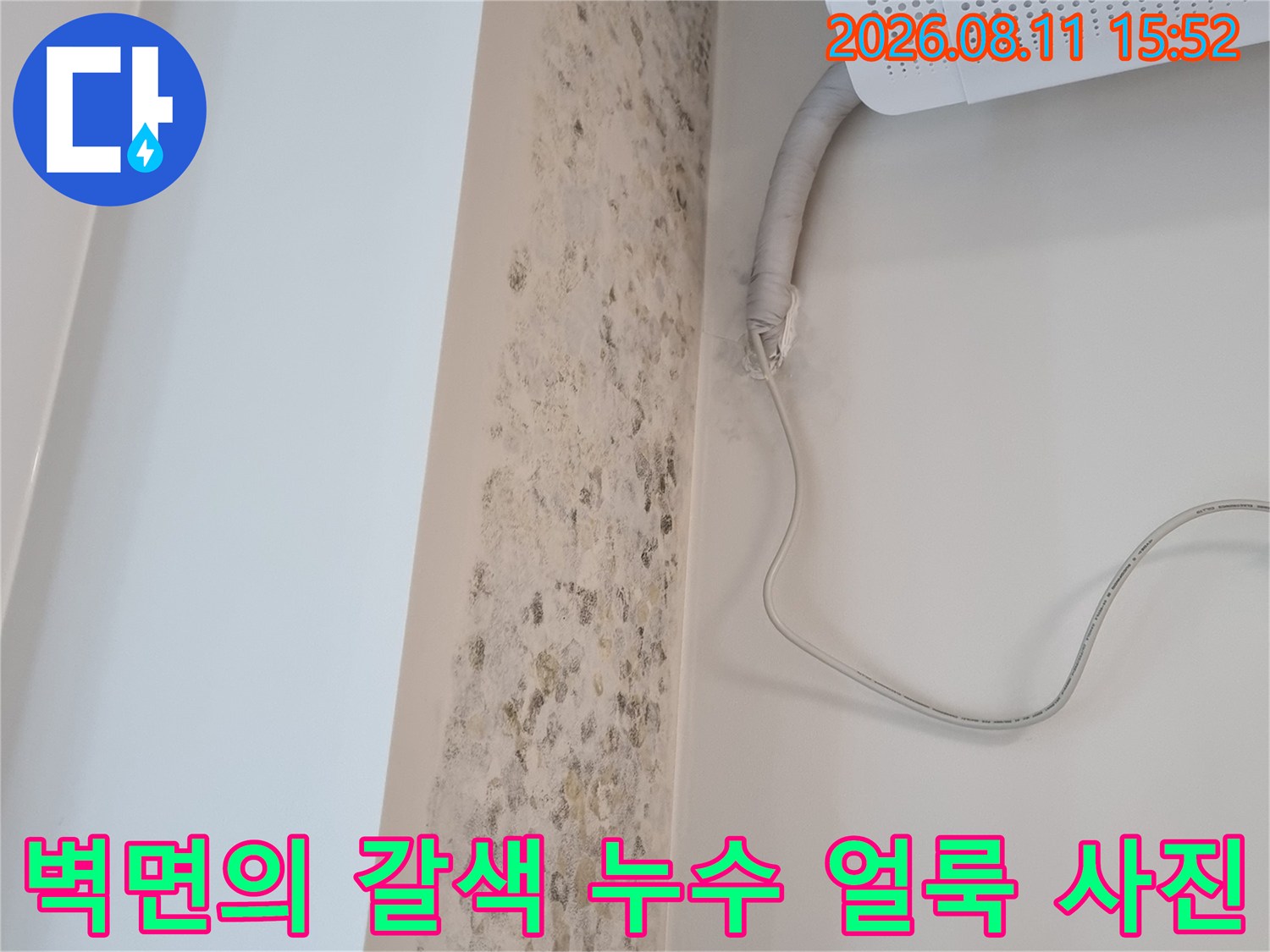 에어컨 드레인 호스 주변으로 습기가 올라와 변색된 흰색 벽면 모습