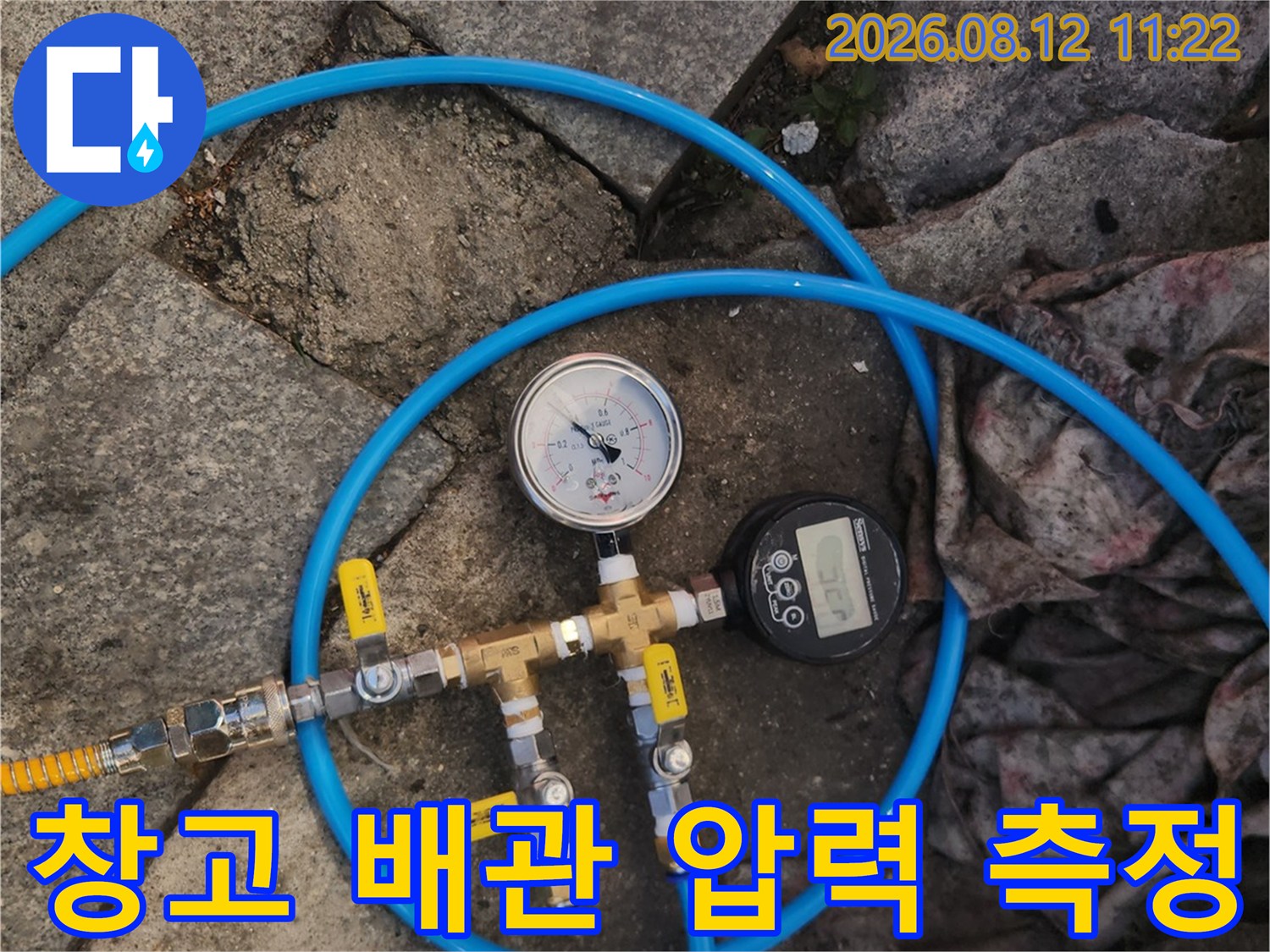 파란색 호스가 연결된 배관 부속 및 게이지
