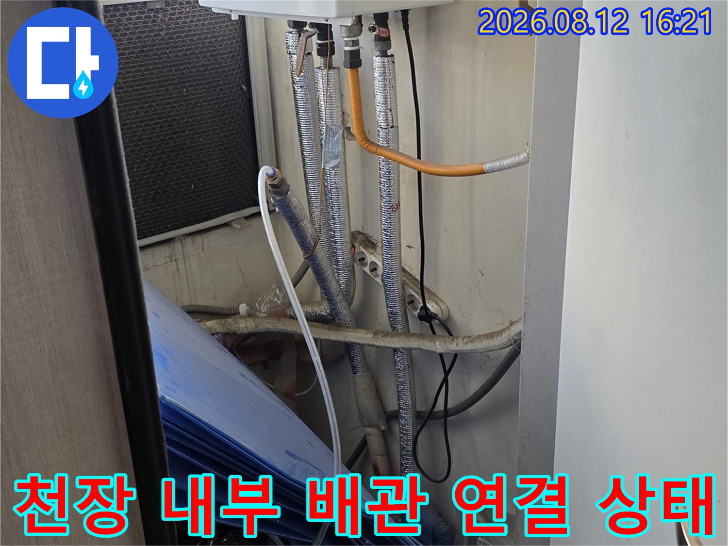 천장 점검구를 통해 본 흰색 보일러 기기와 은색 주름관 배관-연결 부위 모습