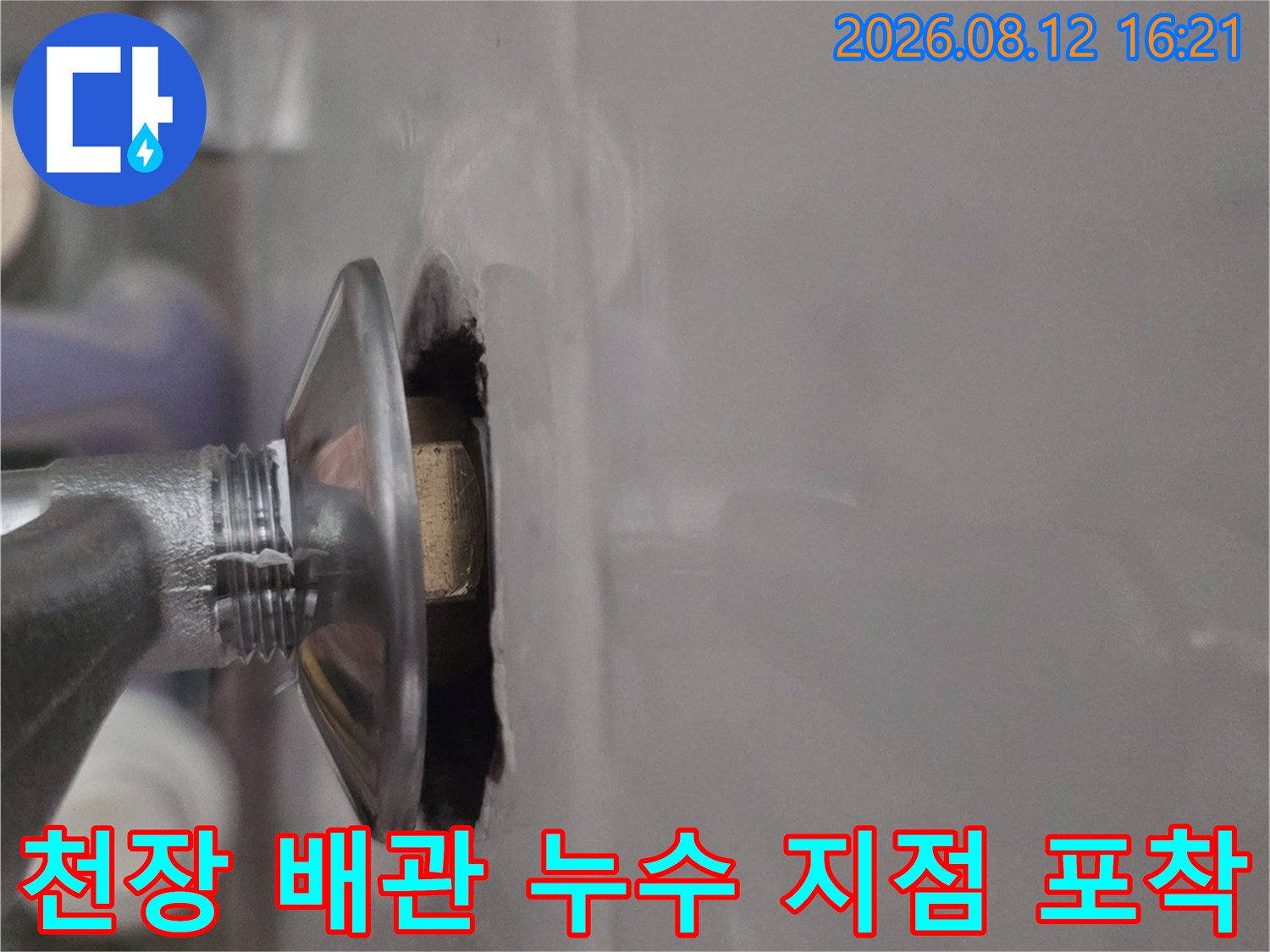 흰색 천장 패널 아래로 돌출된 금속제 파이프 연결 부위 사진