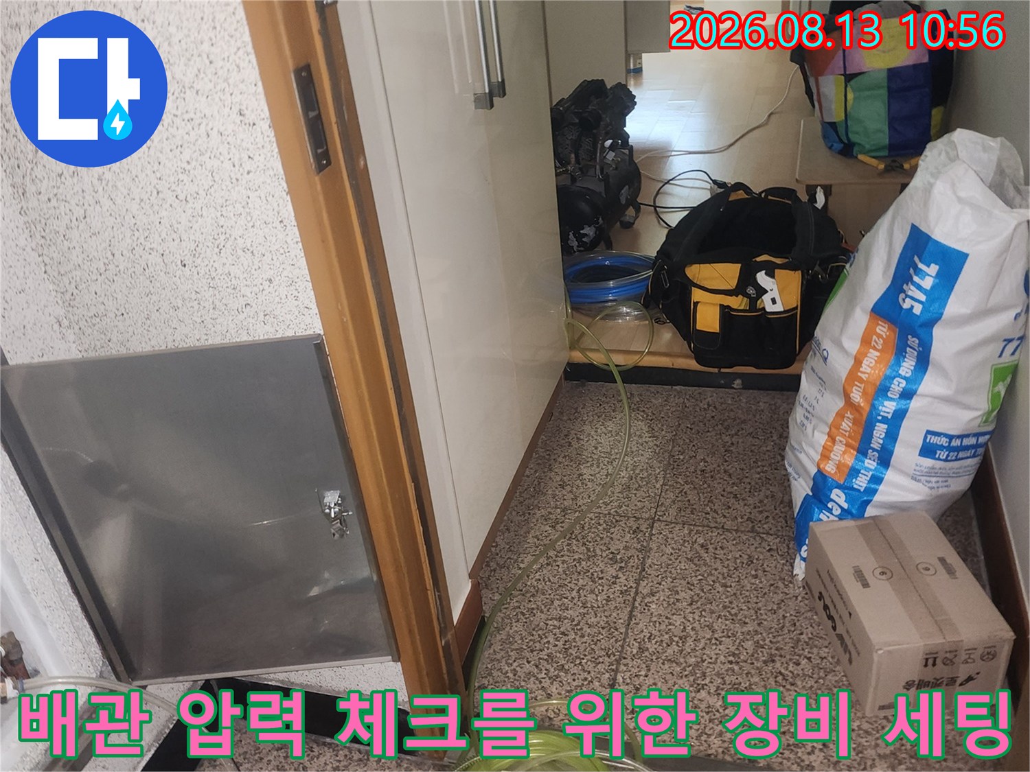 금속 덮개가 열린 점검구 주변으로 노란색과 투명 호스가 배관에 연결된 모습