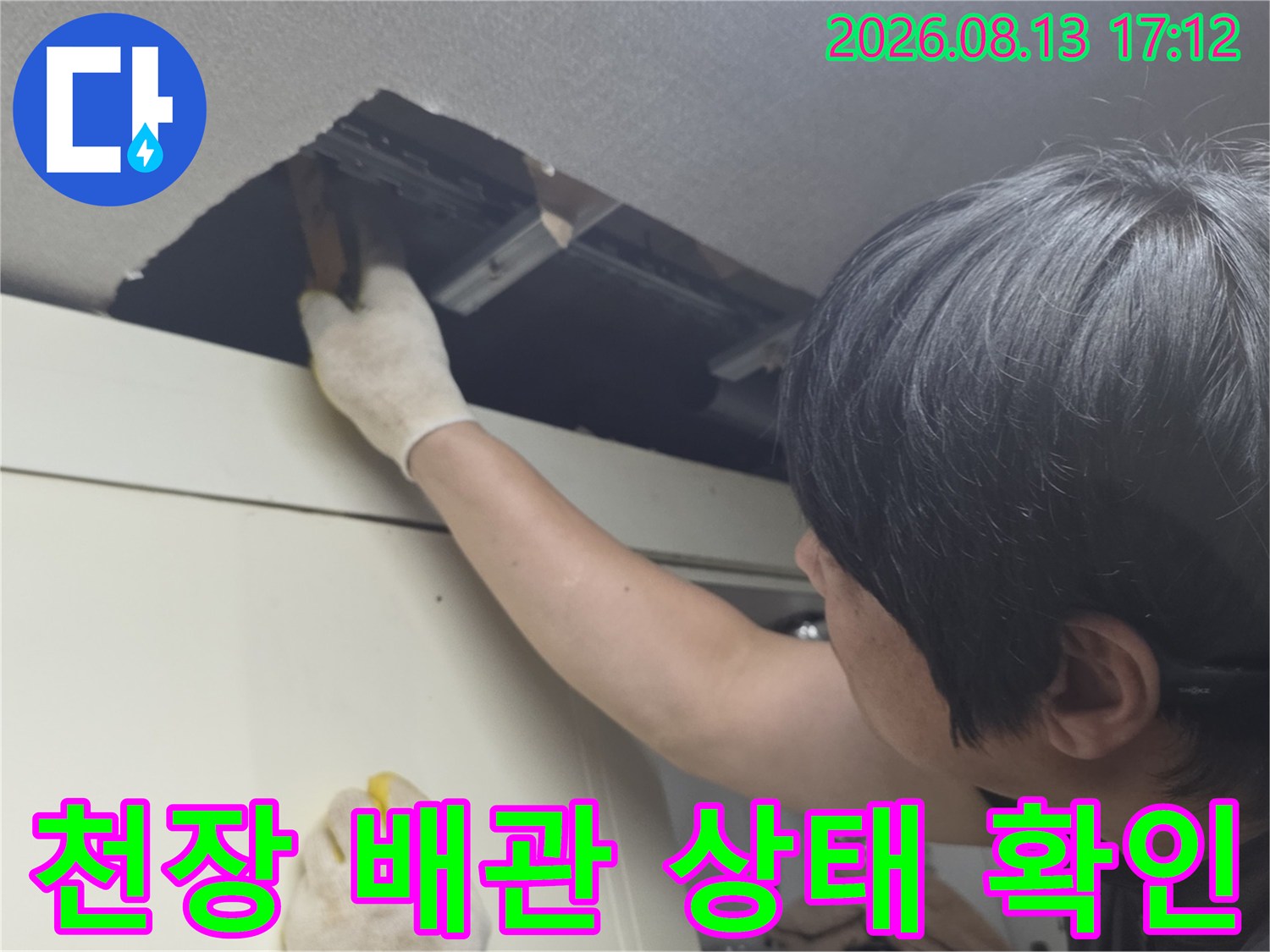 천장 절개 부위를 통해 상부장 뒤쪽 배관의 누수 여부를 점검하는 엔지니어