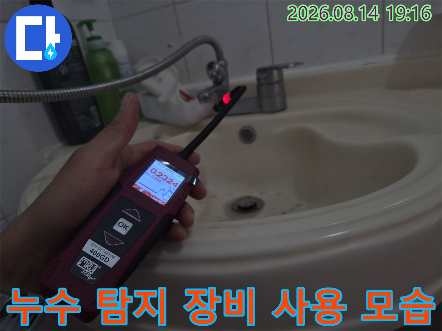 손에 쥔-가스식 누수 탐지기가-세면대 아래 배관을 가리키고 있음