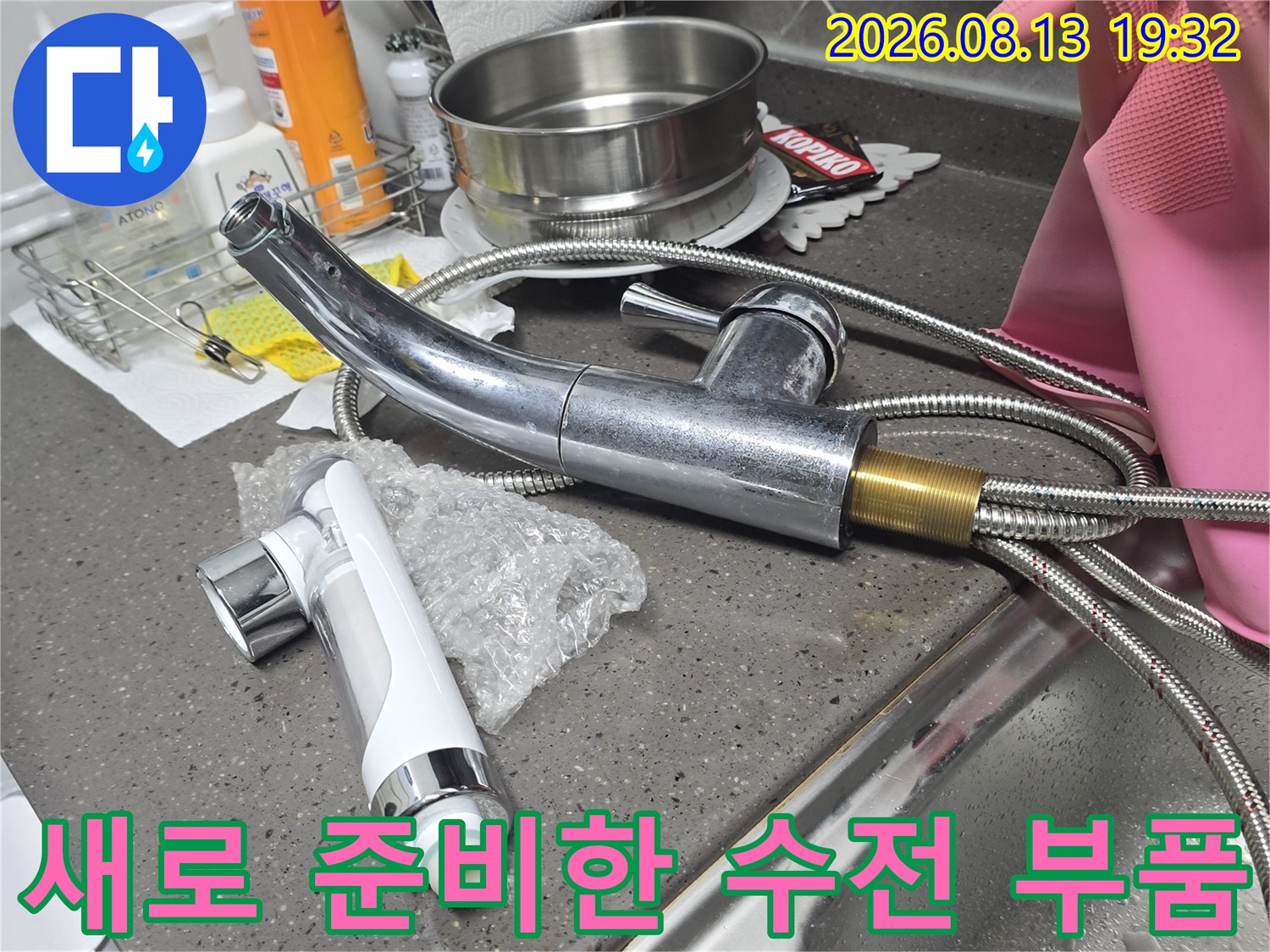 교체 작업을 위해 싱크대 옆에 놓인 새 수전과 호스