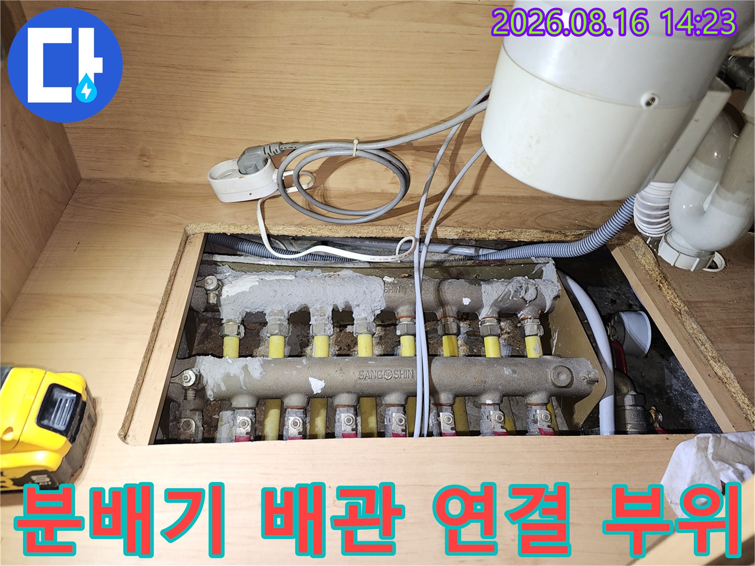 싱크대 아래 분배기에 연결된 여러 개의 노란색 밸브와 배관 모습입니다.