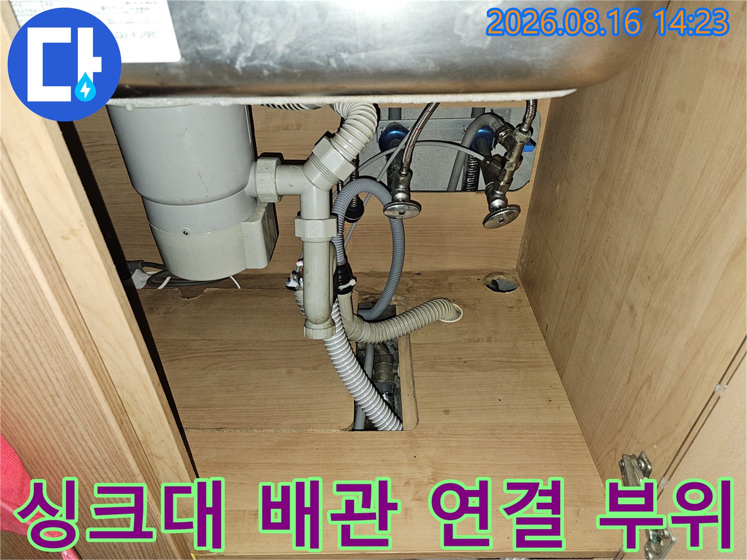 싱크대 하단의 하수관과 급수 호스 연결 상태를 보여주는 사진