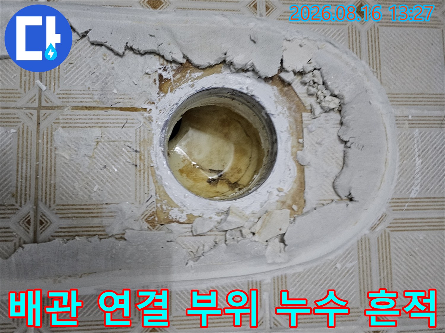 배관 관통 부위 주변의 파손된 마감재와 물이 스며든 흔적을 촬영한 사진입니다.