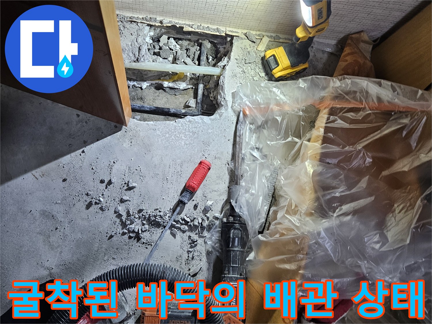 콘크리트 층 아래 노출된 수도 배관과 작업 도구
