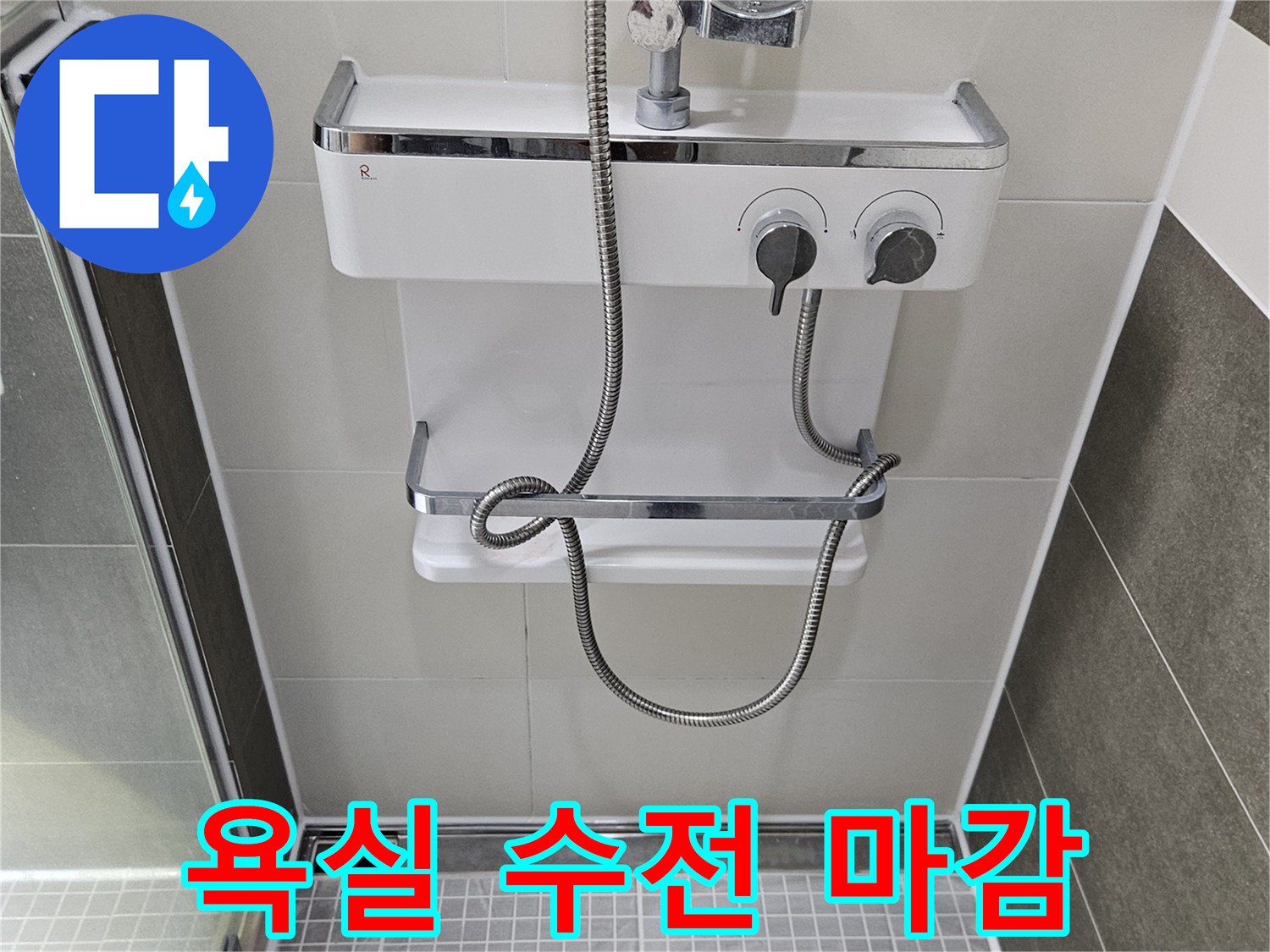샤워기 수전과 은색 호스가 연결된 벽면 타일