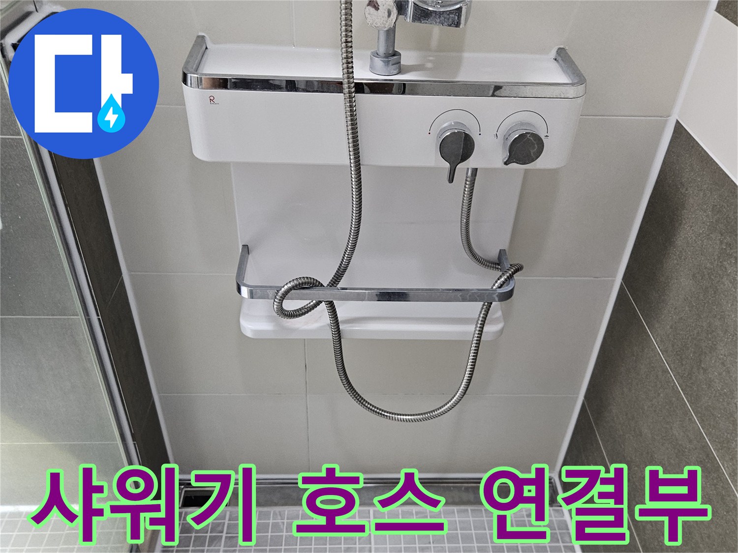 욕실 벽면에 설치된 은색 샤워기 수전과 호스 상세 사진입니다.
