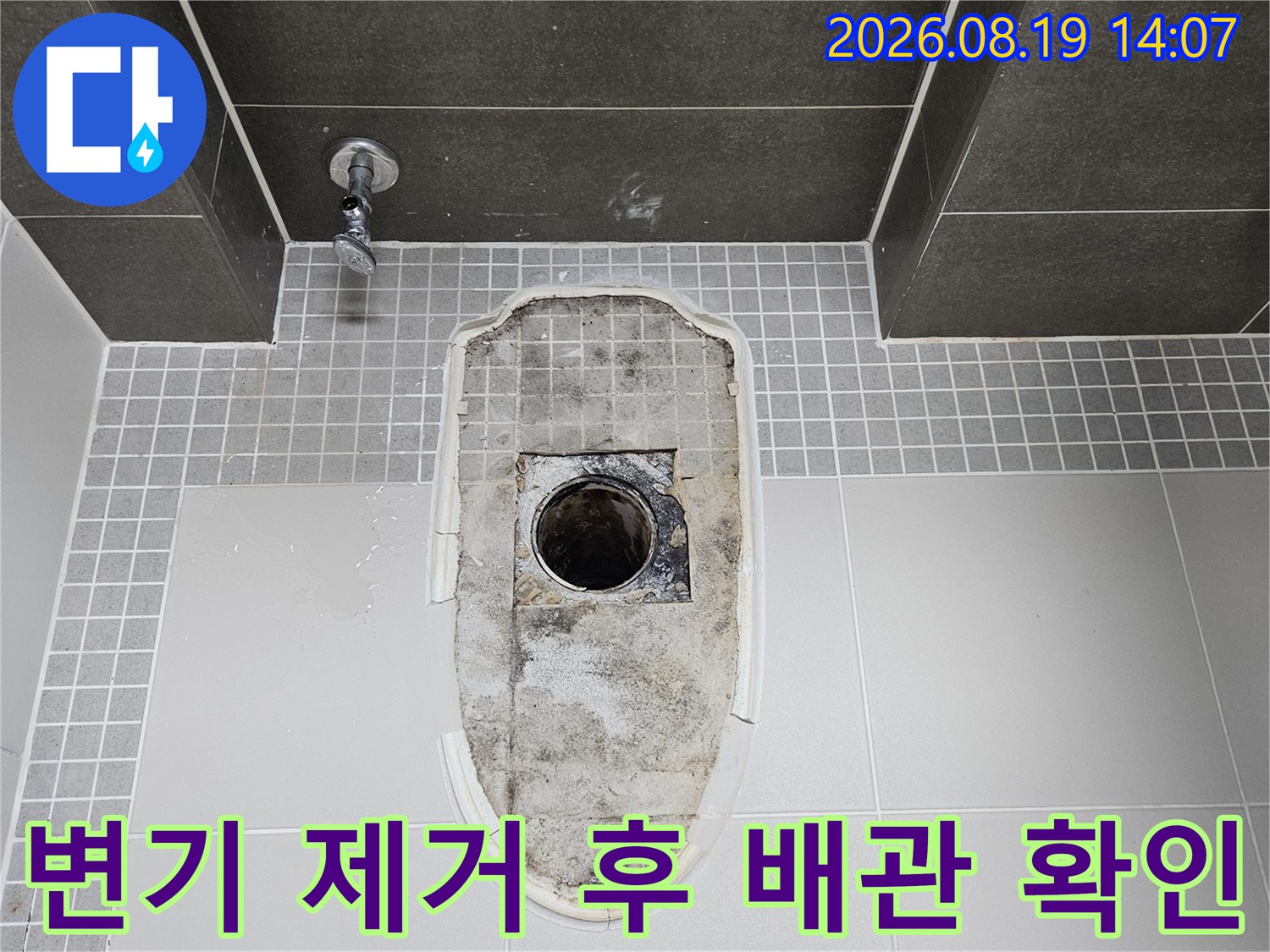 화장실 변기를-제거하여 드러난 오수관과 젖은 타일 표면