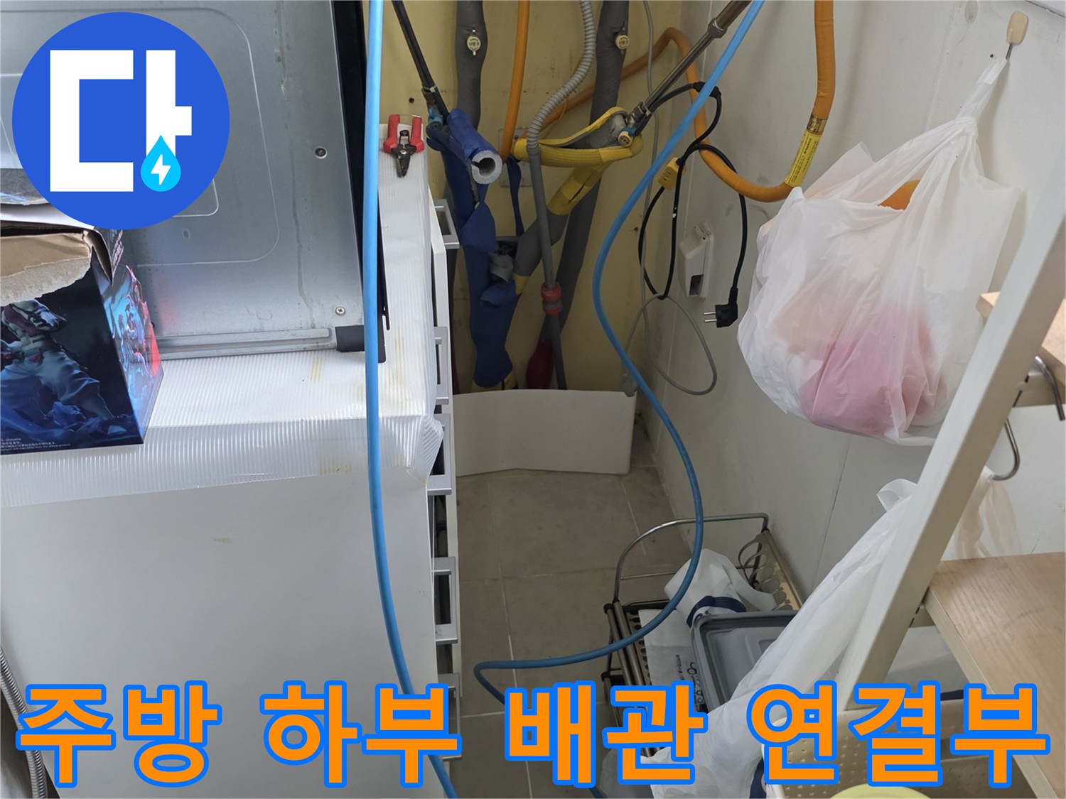 싱크대 밑에 설치된 노란색 수도 배관과 파란색 정수기 호스의 연결 상태를 보여줍니다.